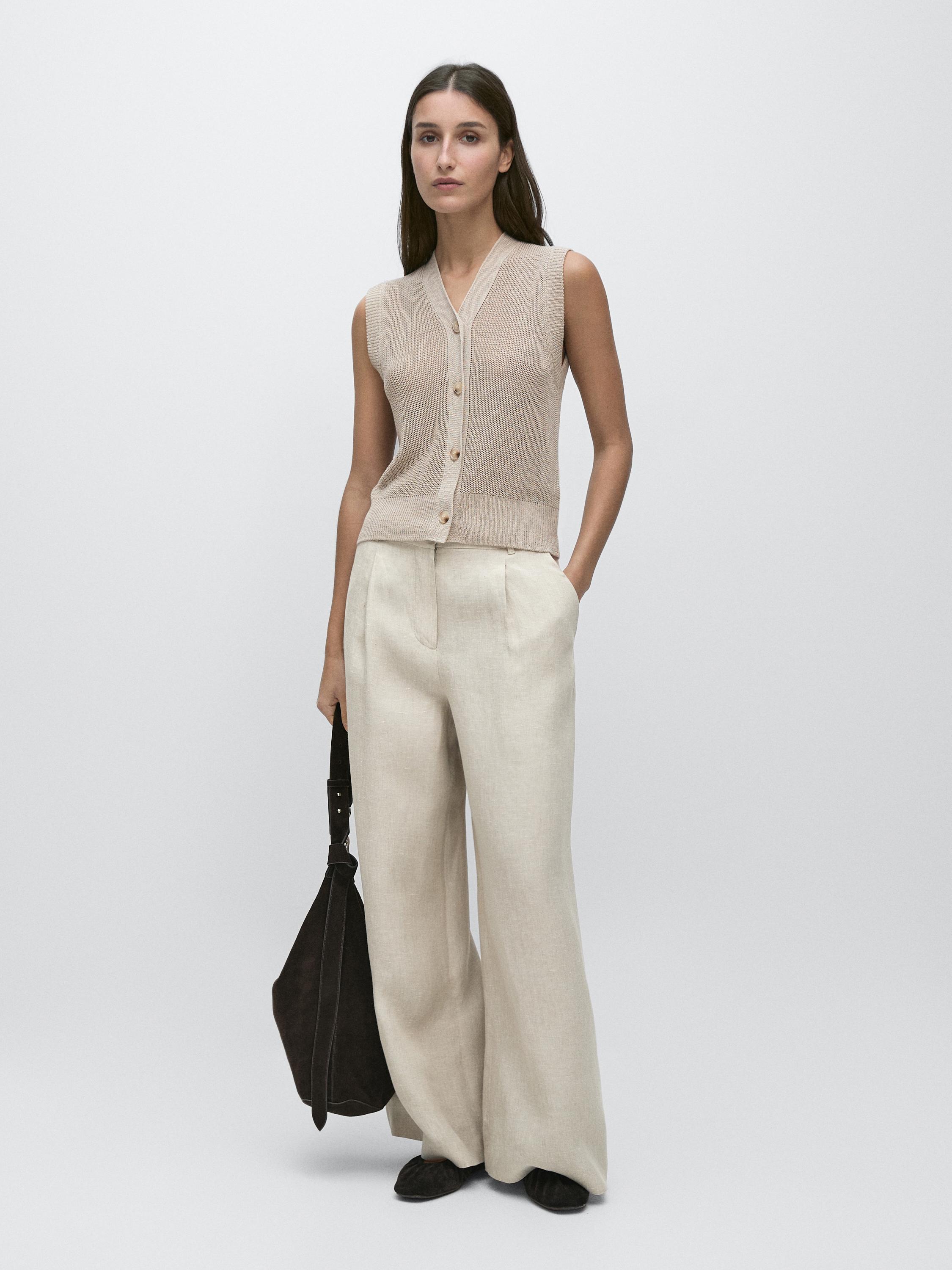 Conjunto de chaleco gris topo sin mangas con botones y pantalones anchos beige con bolsillos laterales.