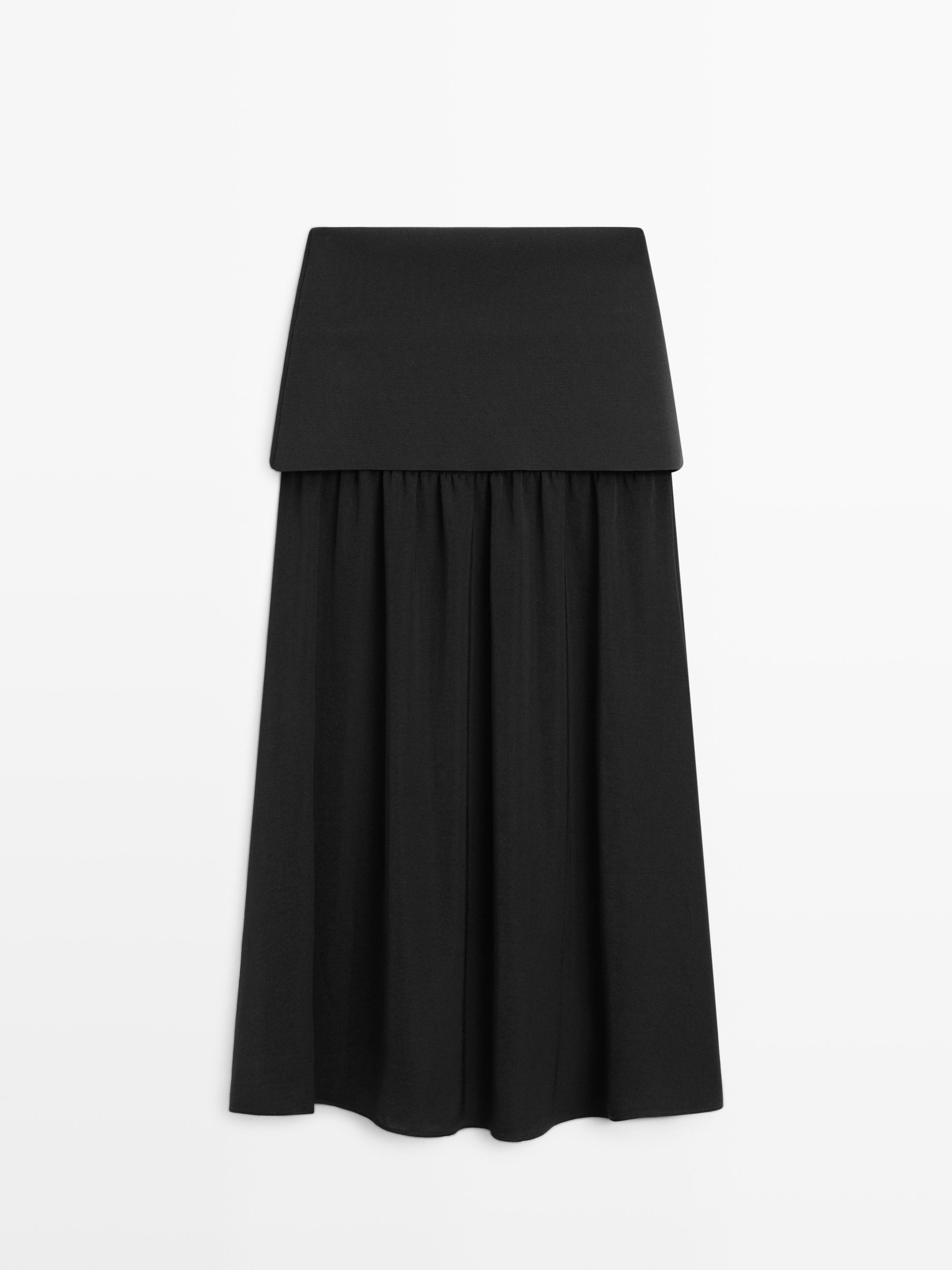 Vooraanzicht van een zwarte tricot rok met brede tailleband en losse pasvorm.