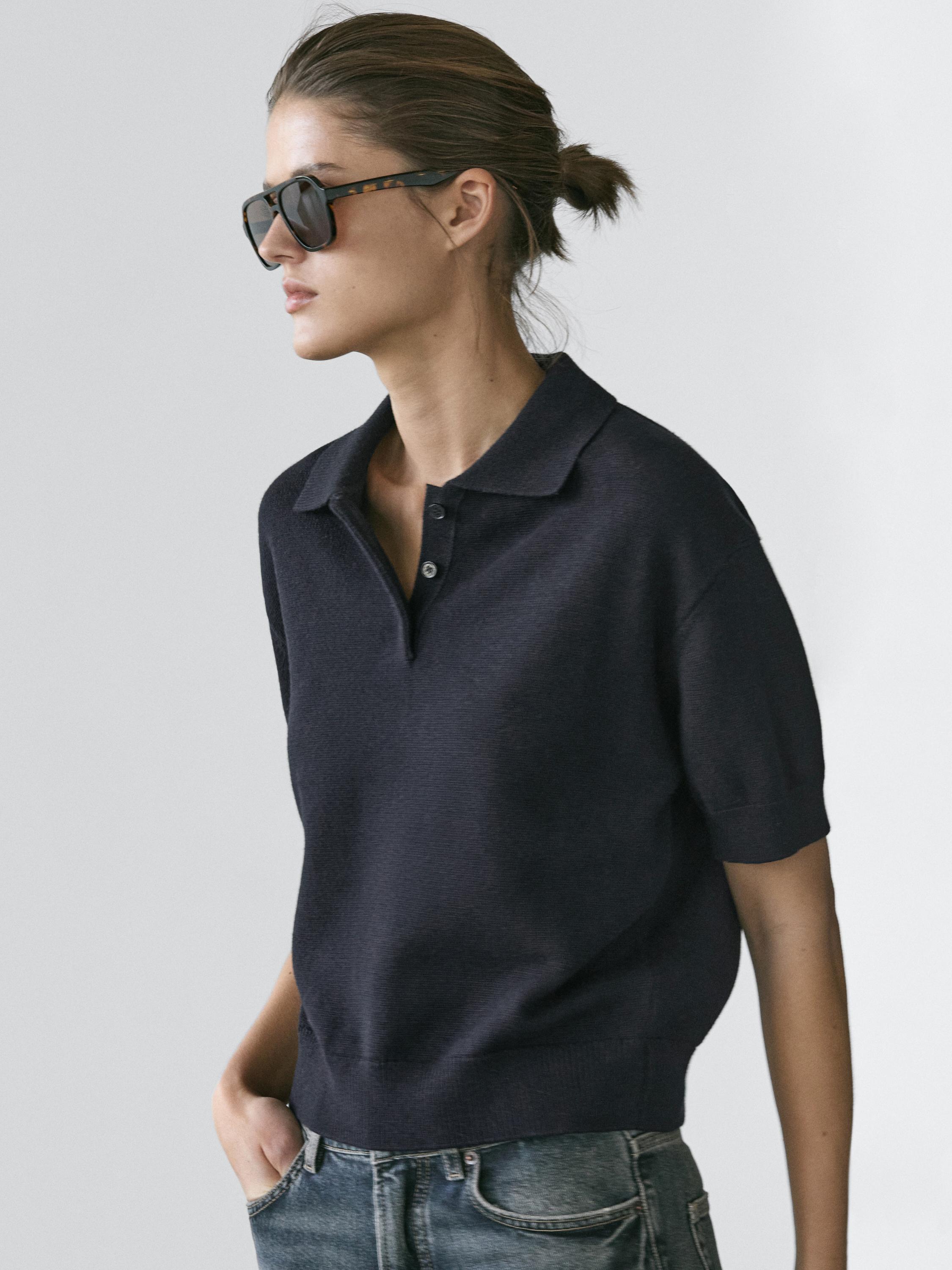 "لقطة متوسطة لتيشيرت بولو كحلي محبوك بأكمام قصيرة وياقة كلاسيكية."