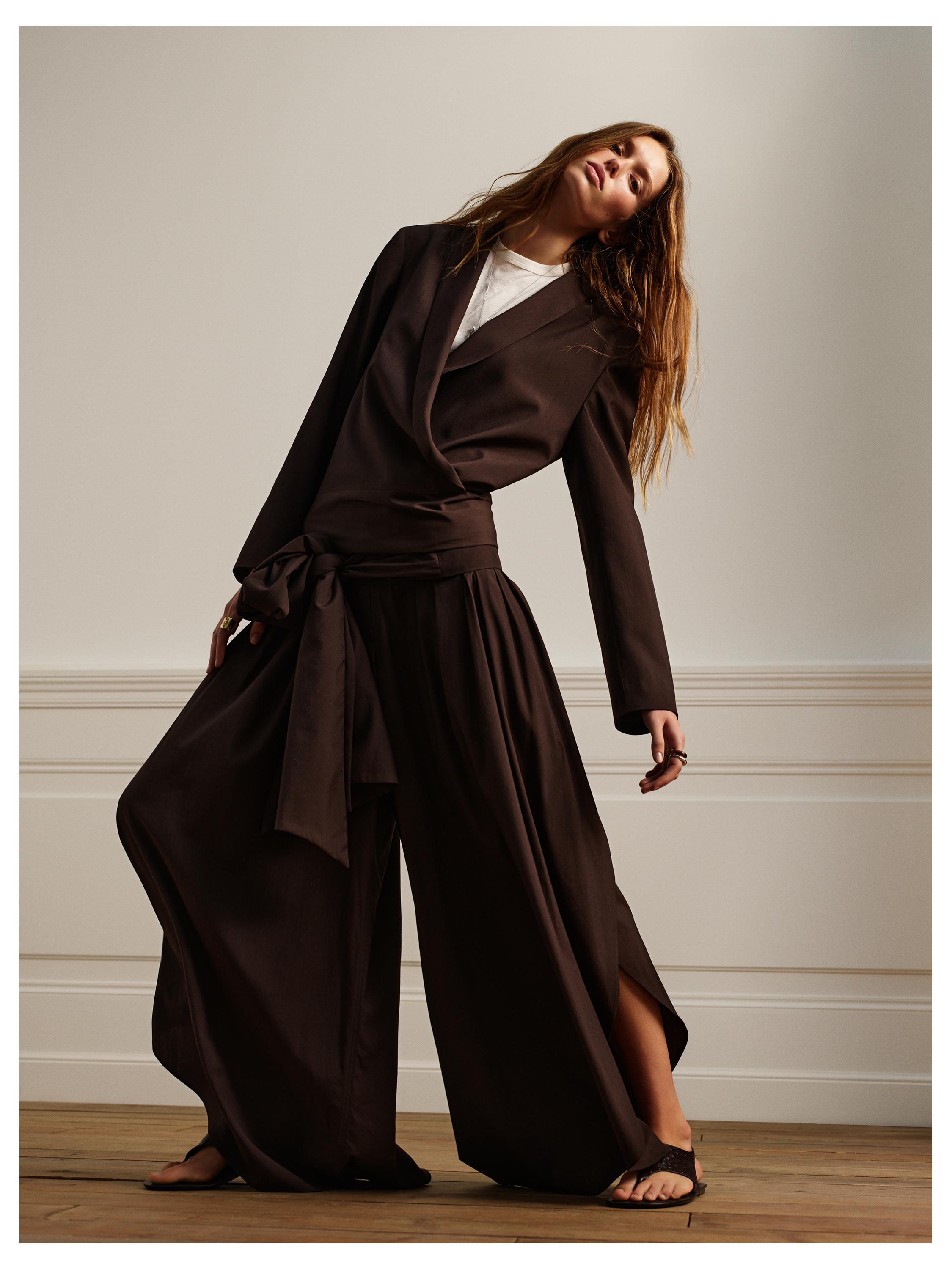 Σετ καφέ σακάκι με ζώνη και ασορτί φαρδύ παντελόνι, πάνω από λευκό T-shirt.