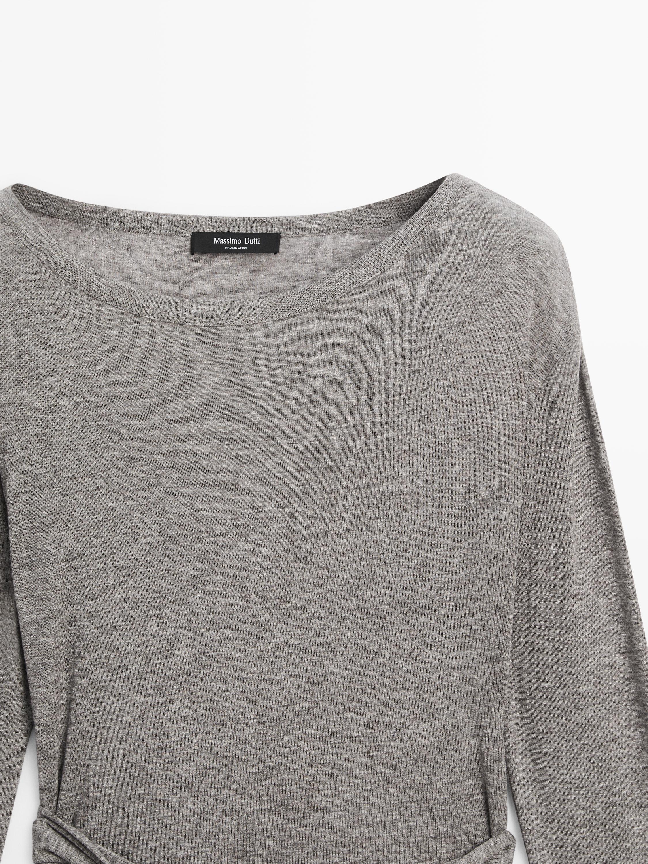 Pamje nga afër e bluzës gri vigoré me mëngë të gjata, qafë të rrumbullakët dhe detaj me lidhëse në bel.