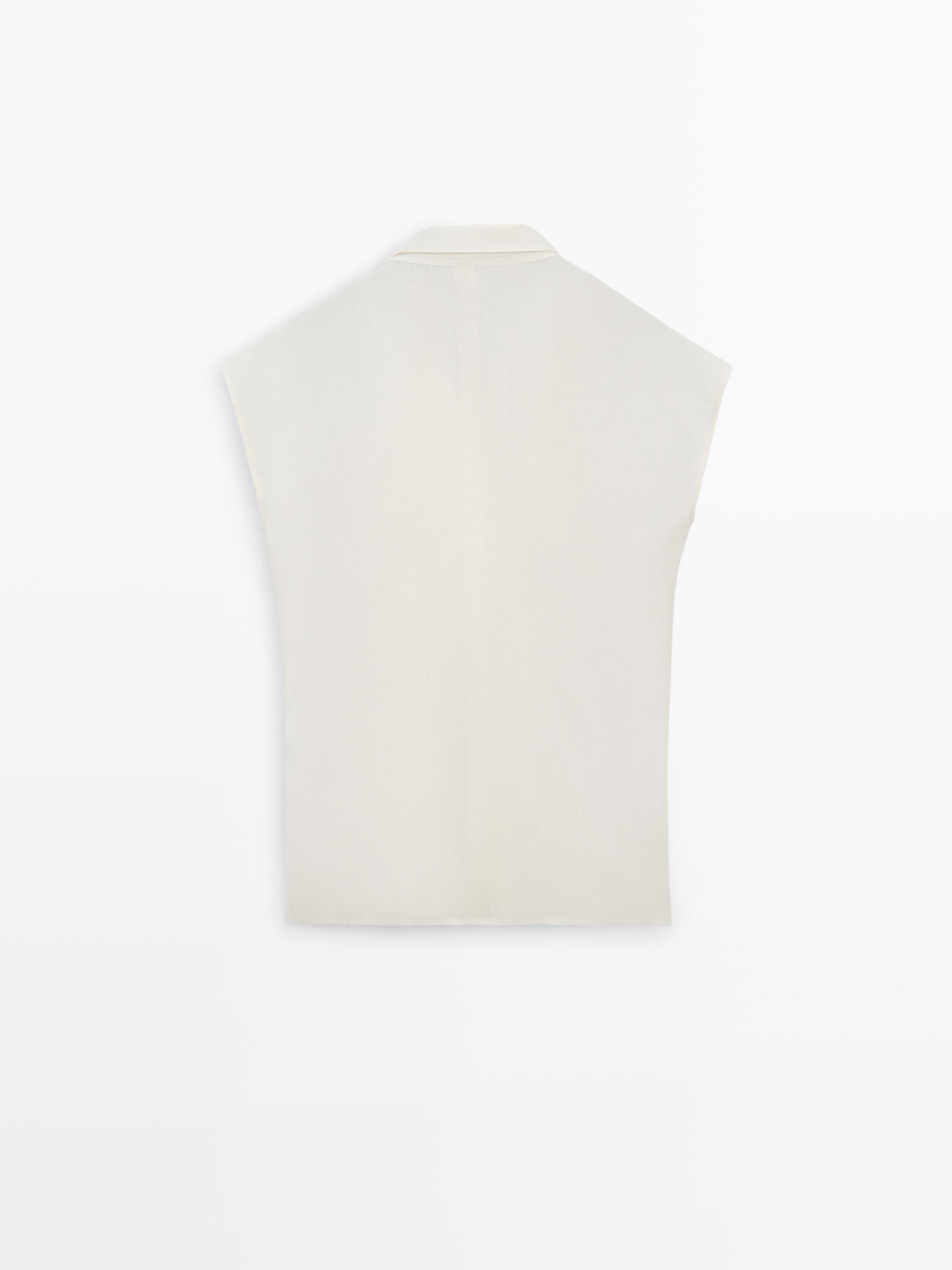 Vista posterior de blazer blanco roto sin mangas, con cuello clásico.