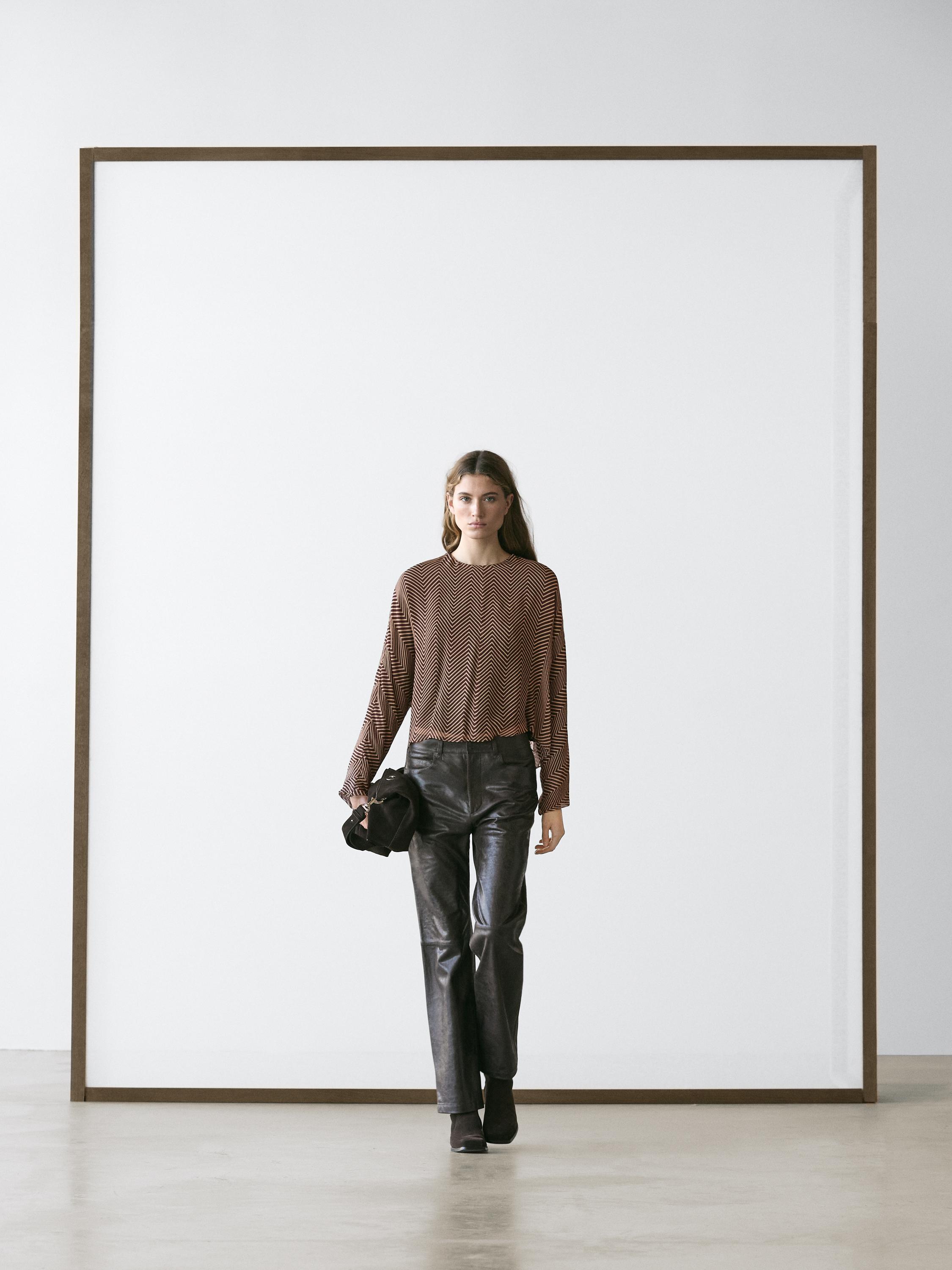 Conjunto de blusa burdeos estampada con pantalones negros rectos y botines oscuros.