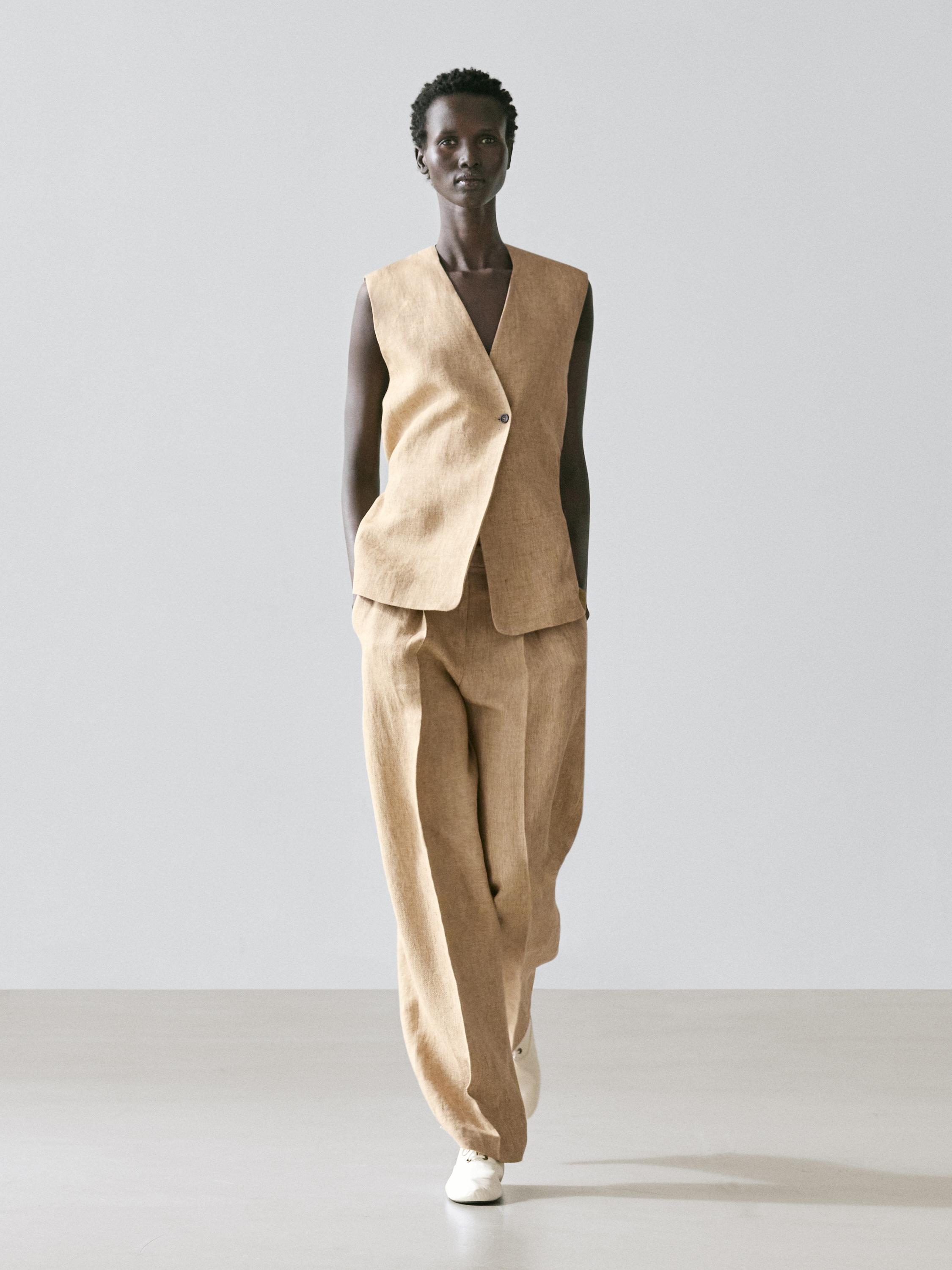 Conjunto de chaleco beige de cierre cruzado y pantalones anchos a juego, con bolsillos laterales visibles.