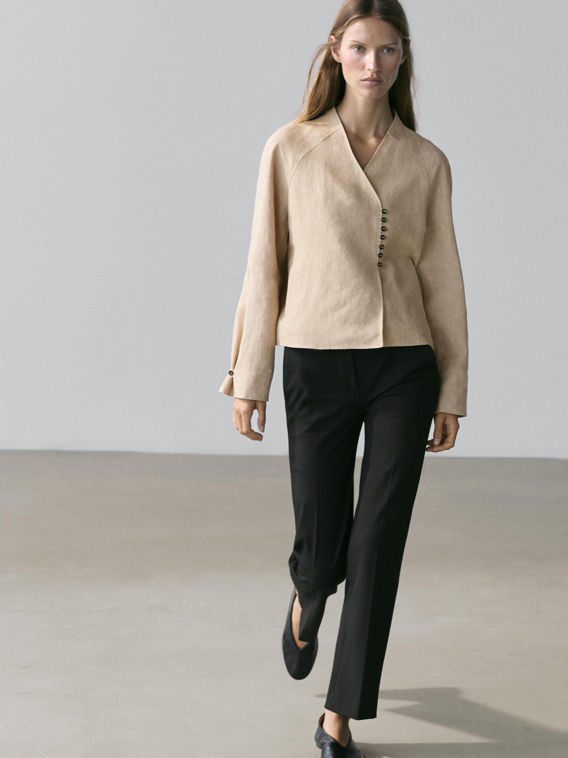 Beige cropped jacket set with side buttons and straight black pants.