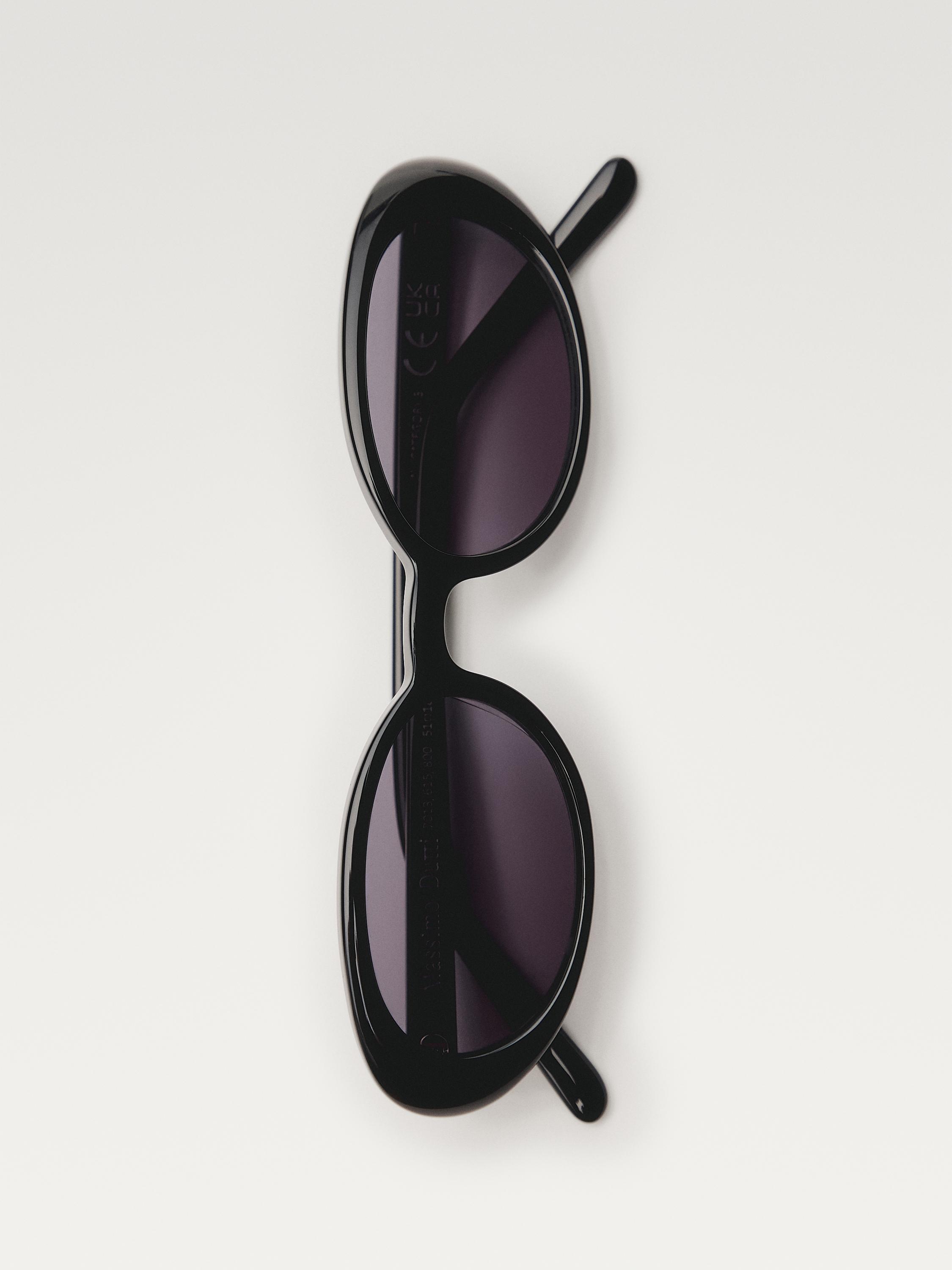 Vista frontale di occhiali da sole neri con lenti ovali scure e aste sottili. Dimensioni: 51-18-140 mm.