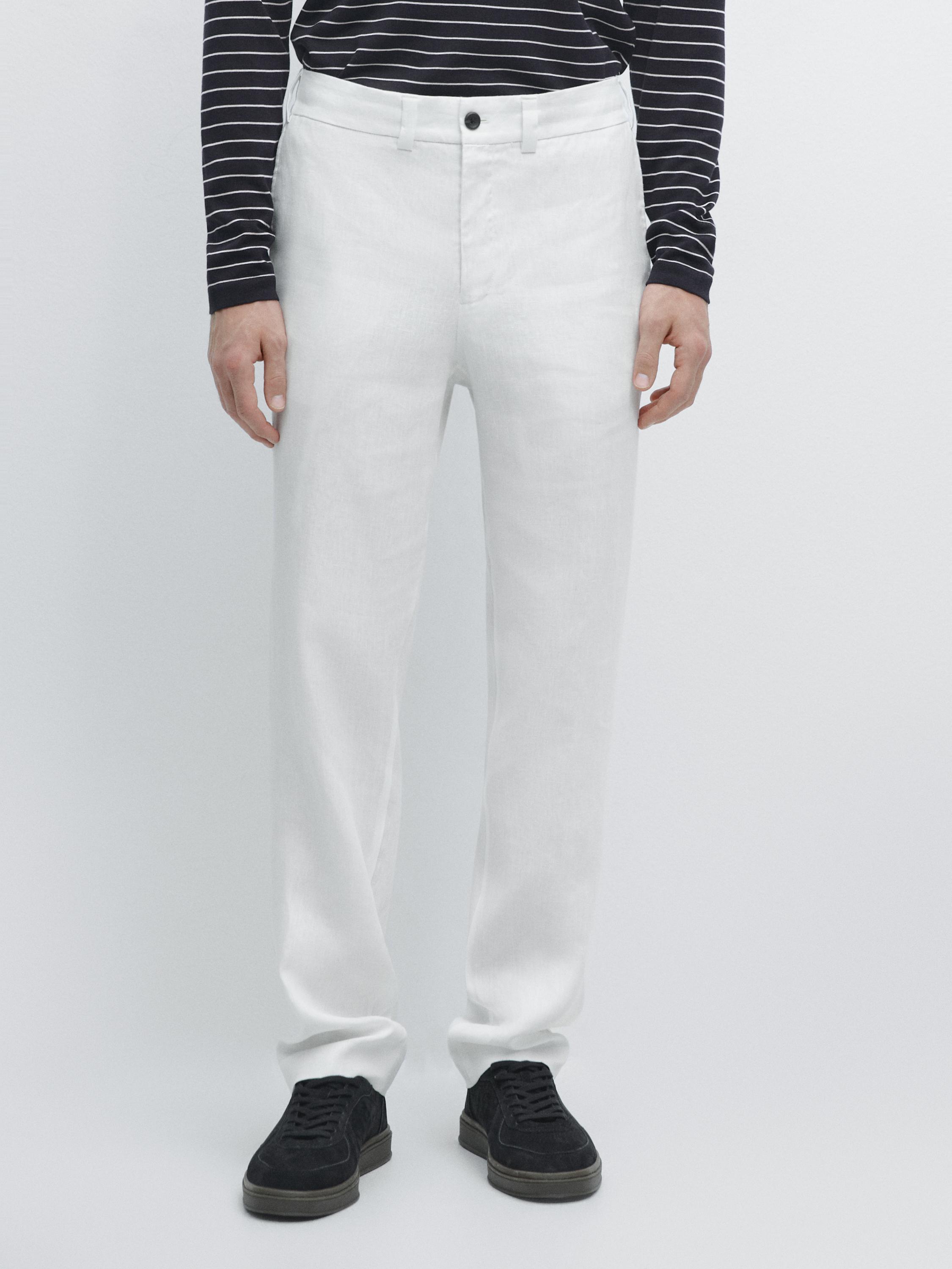 Conjunto de pantalón blanco con cintura elástica y botón frontal, bolsillos laterales, camiseta de rayas negras y zapatillas negras.