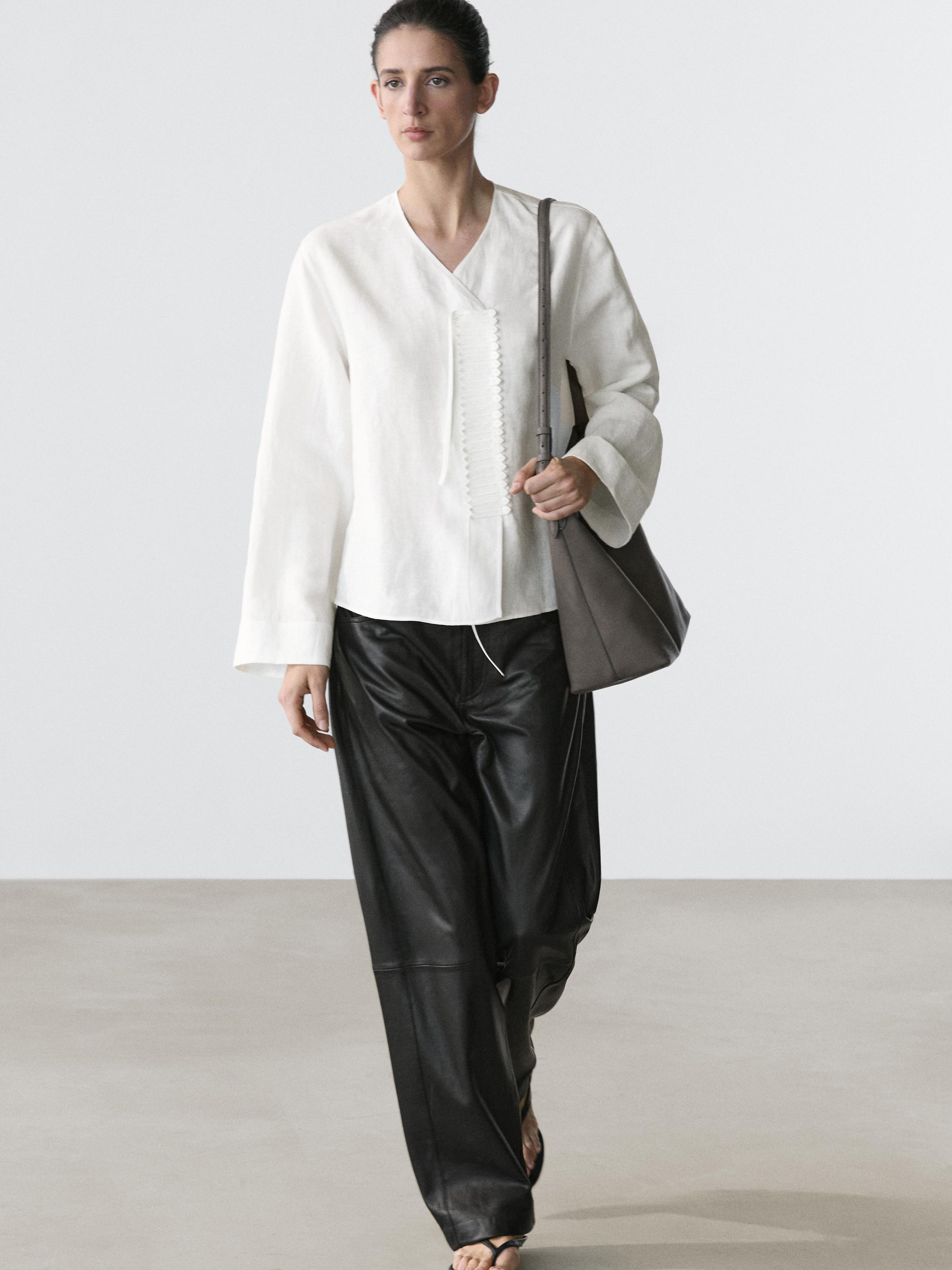 Conjunto de camisa blanca con detalle en pechera y pantalones negros anchos.