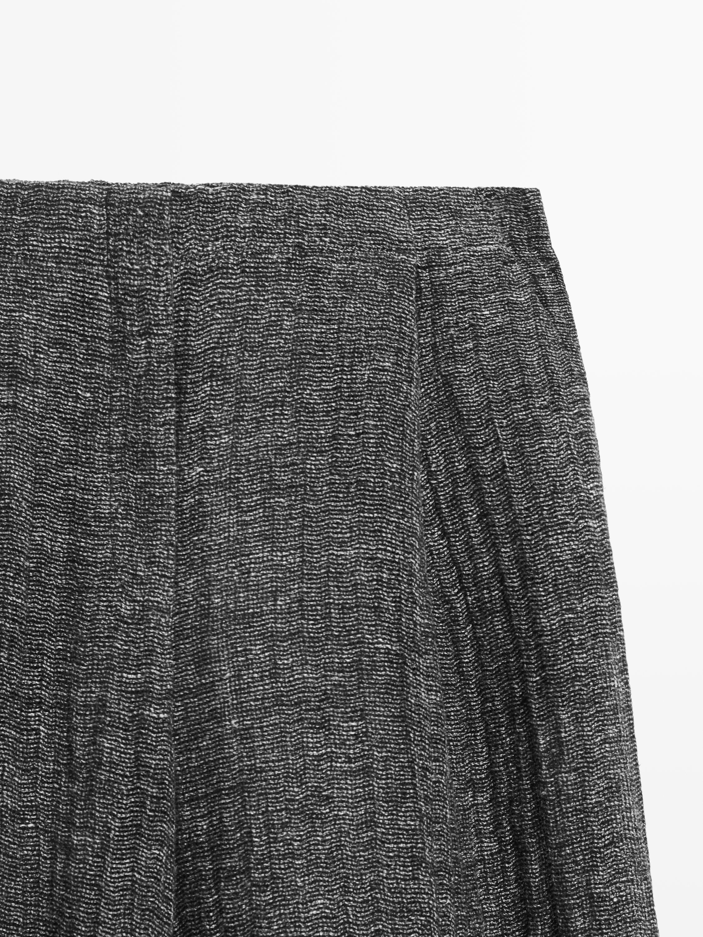 "Detalle de la parte superior de un pantalón gris con textura y pliegues visibles."