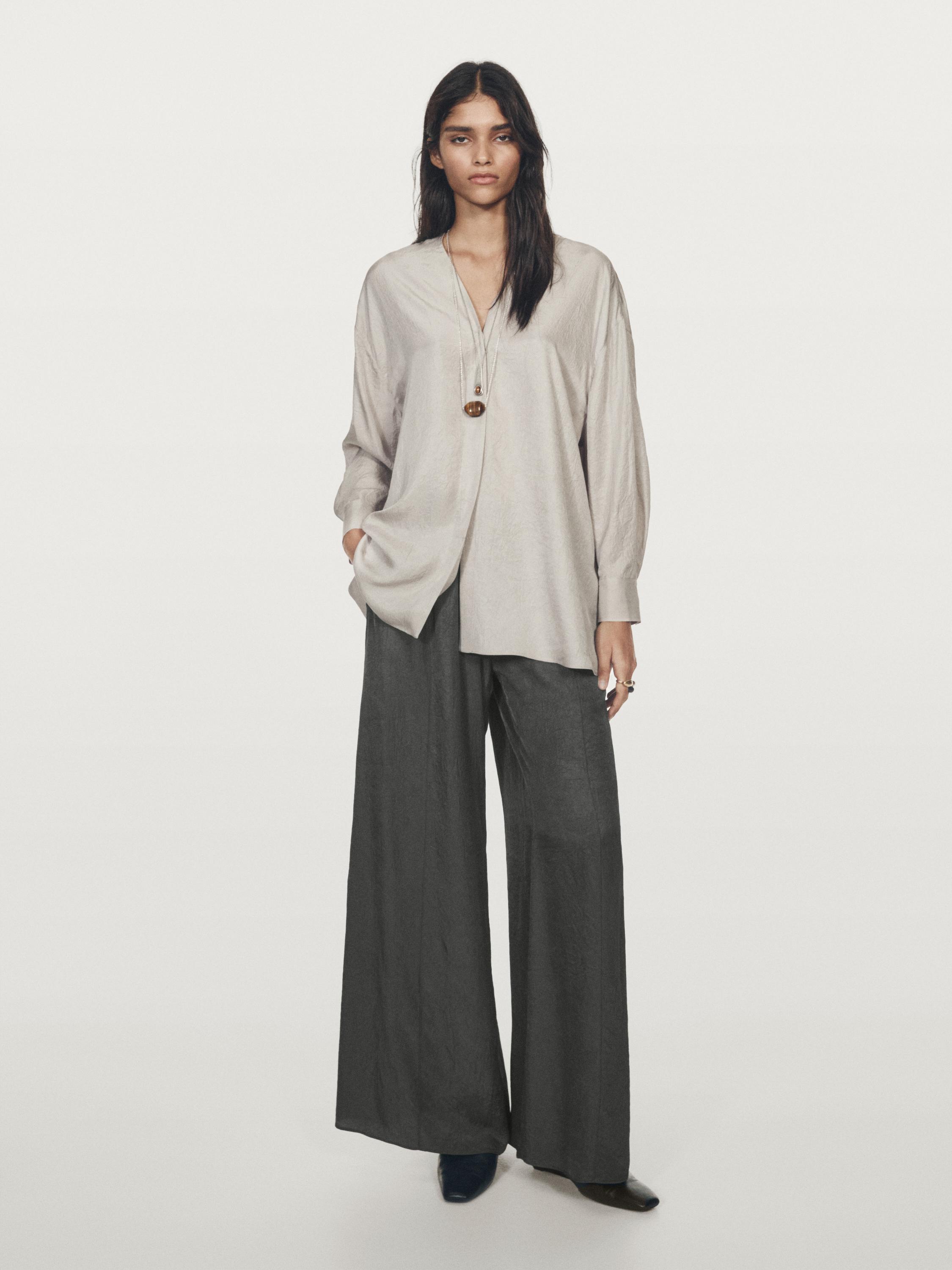طقم مكون من قميص فضفاض بلون فاتح بياقة على شكل حرف V وبنطلون واسع داكن.