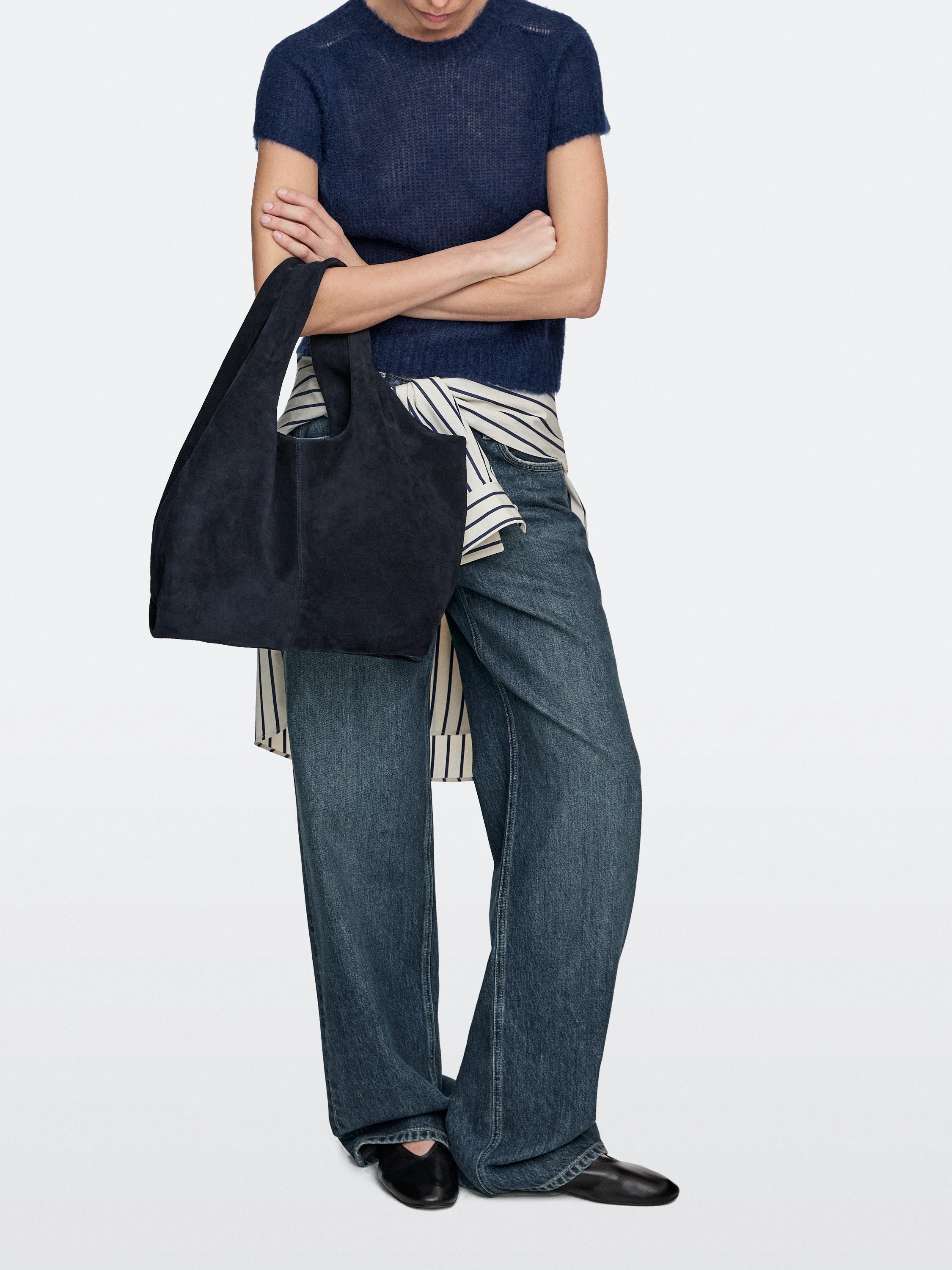 To'q ko'k rangli shopper sumka, ko'k futbolka, keng jinsi shimlar va qora tufli to'plami.