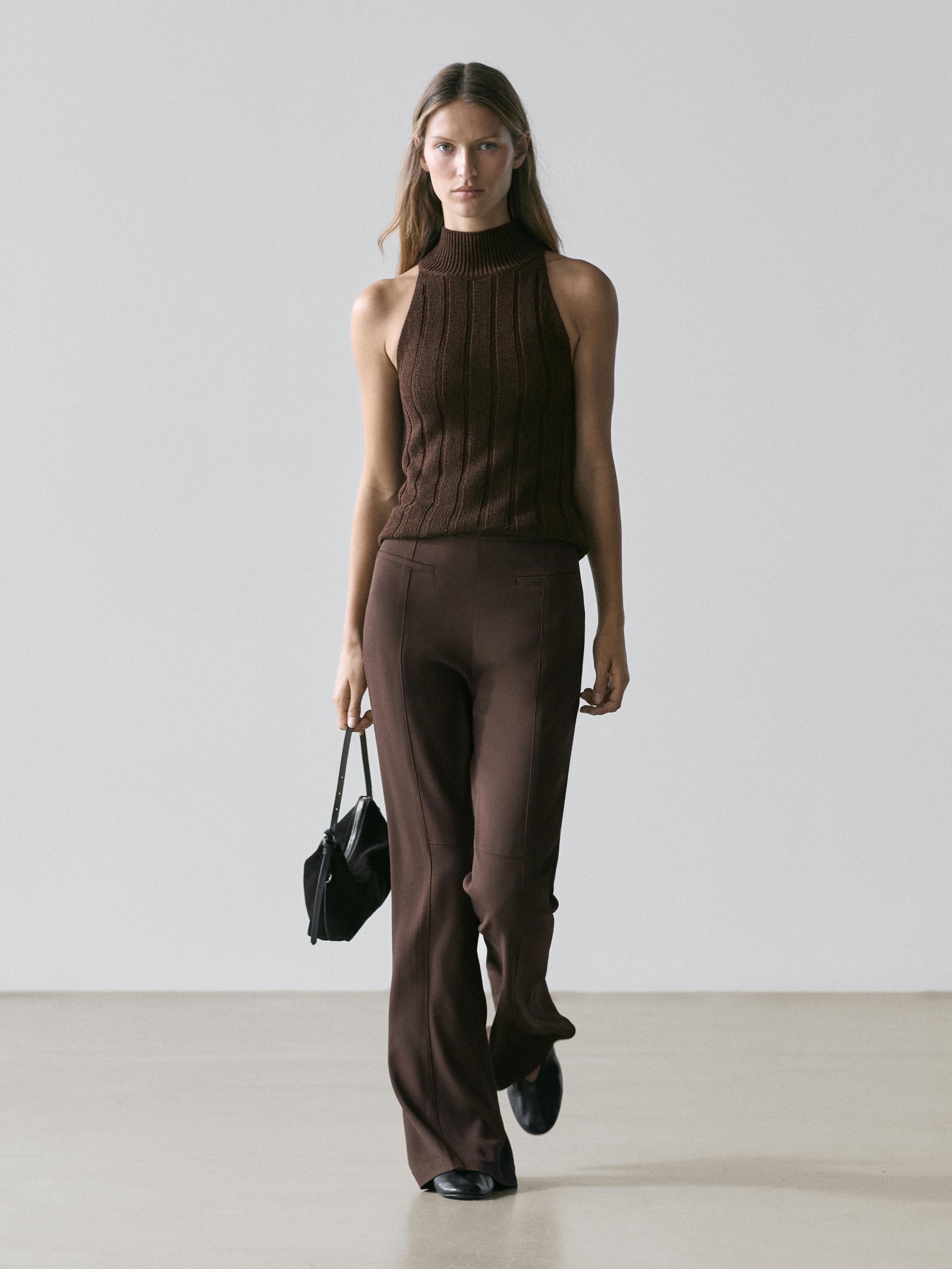 Brown flare-cut pants set with pockets and brown sleeveless high-neck top.