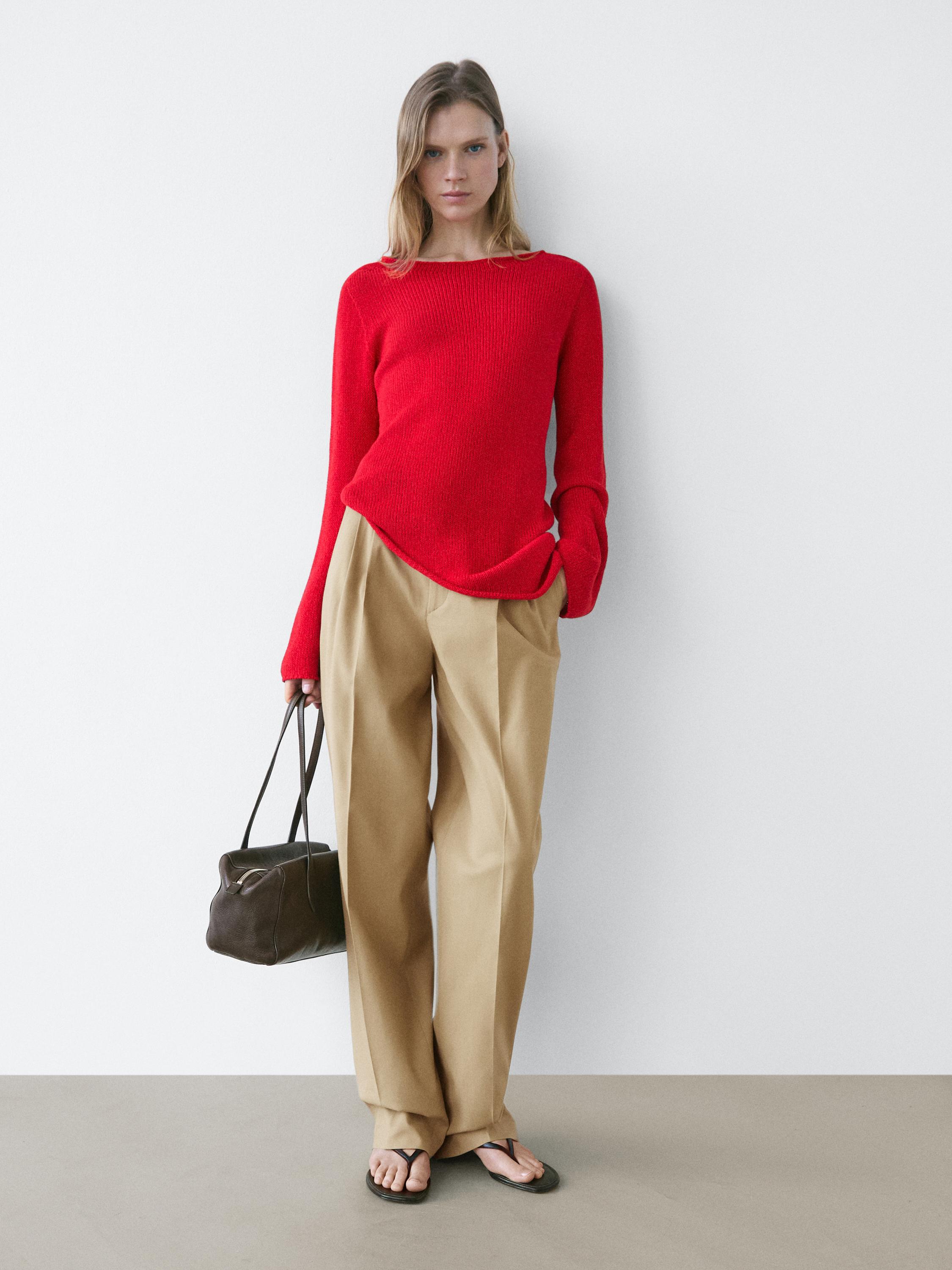 Conjunto de pantalón recto arena con pliegues y suéter rojo de manga larga.