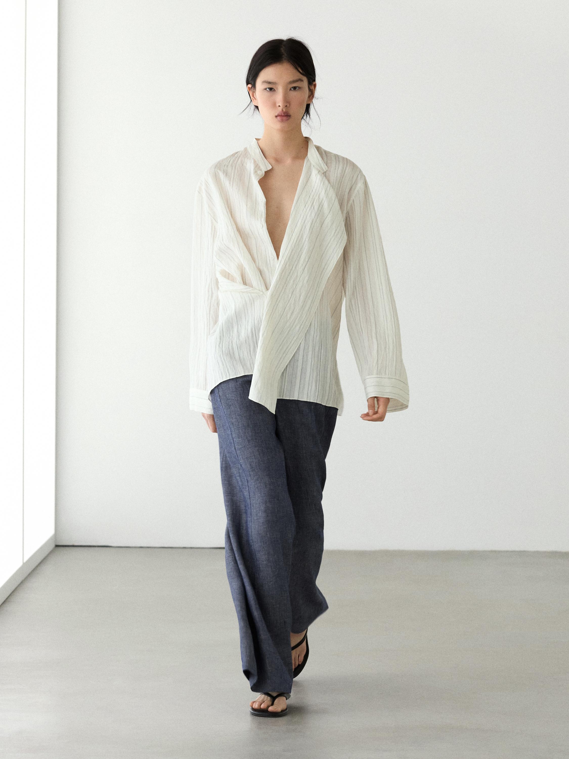 Conjunto de pantalón palazzo azul oscuro de tiro alto y blusa blanca cruzada de manga larga.