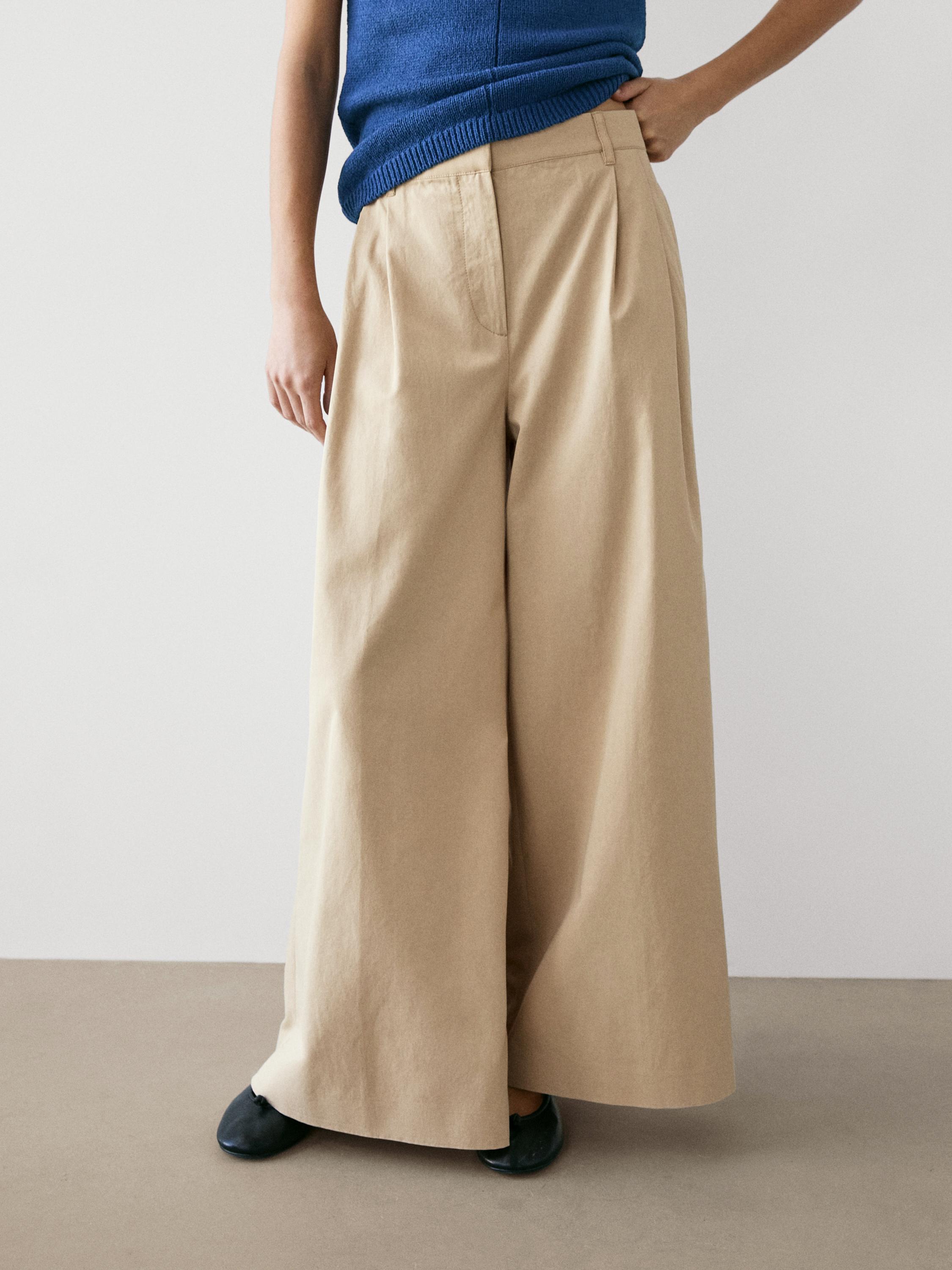 Plano medio de pantalón fluído area con pregos frontais e petos laterais.