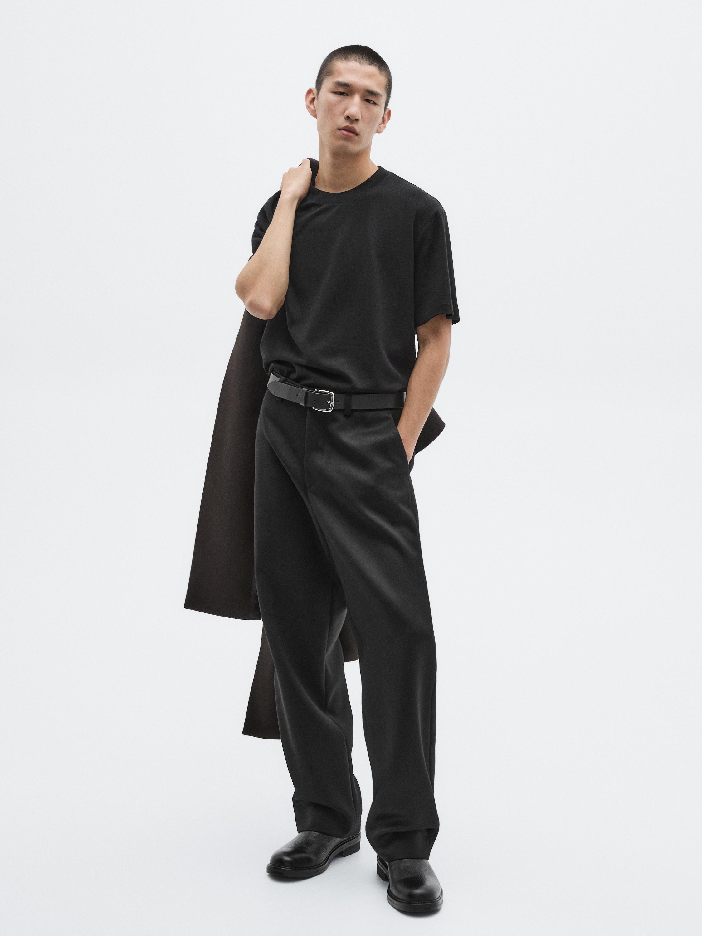 طقم يتكون من تي شيرت أسود بأكمام قصيرة، بنطال أسود بقصة مستقيمة مع حزام، وحذاء أسود.