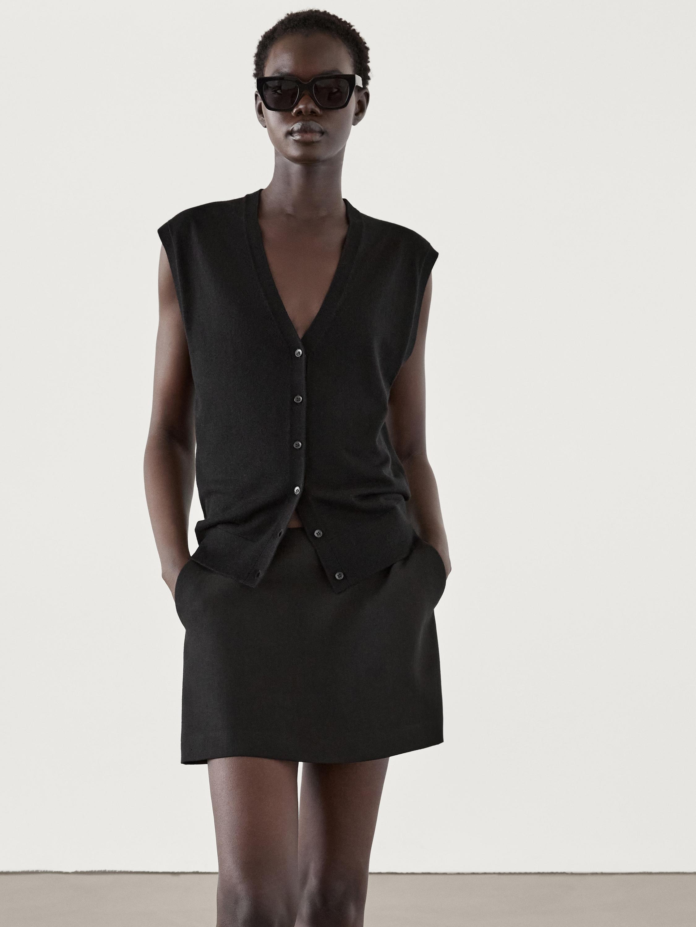 طقم صدرية سوداء بدون أكمام وتنورة قصيرة سوداء بجيوب جانبية