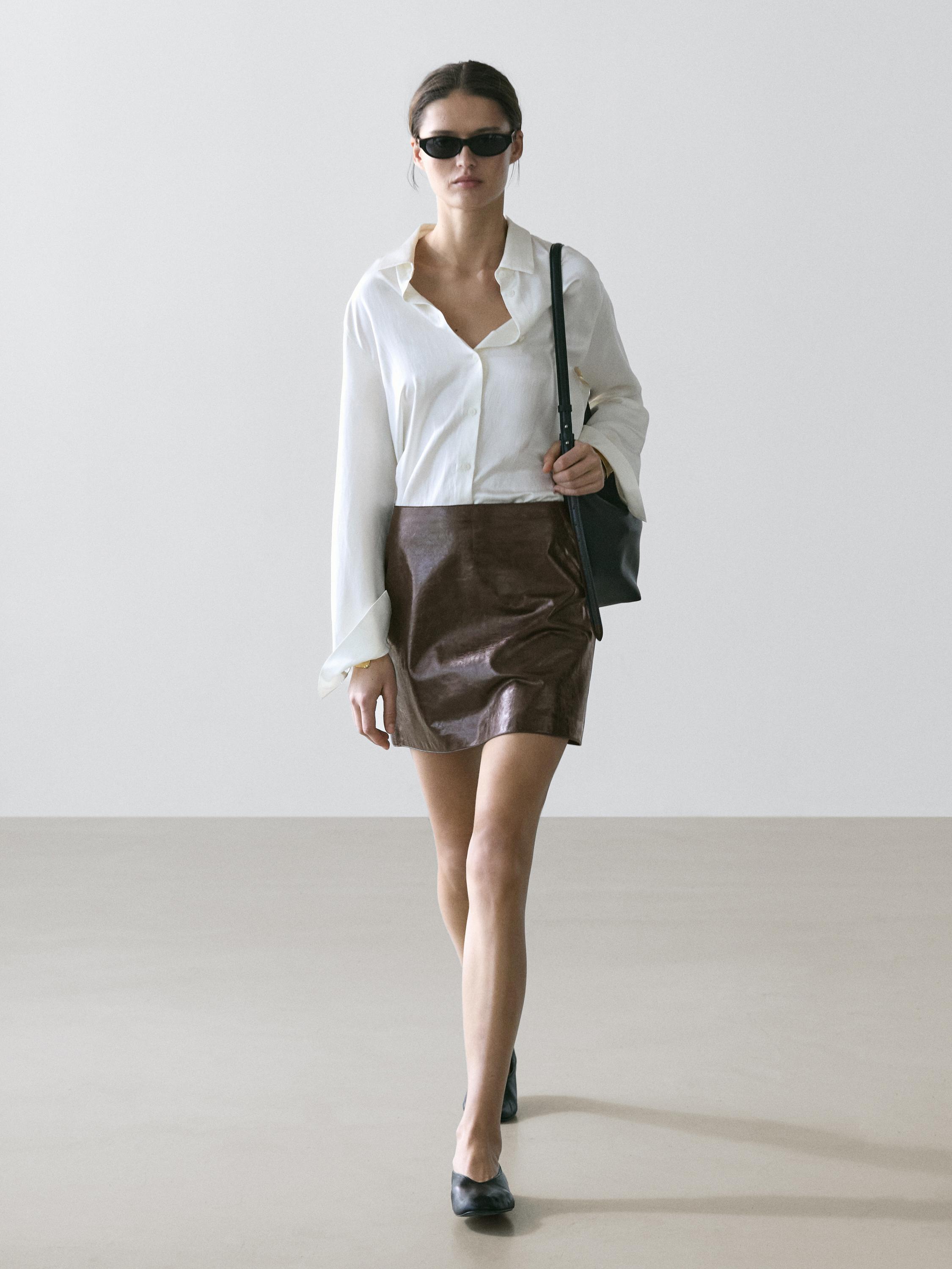 Long-sleeved white shirt and brown mini skirt set.
