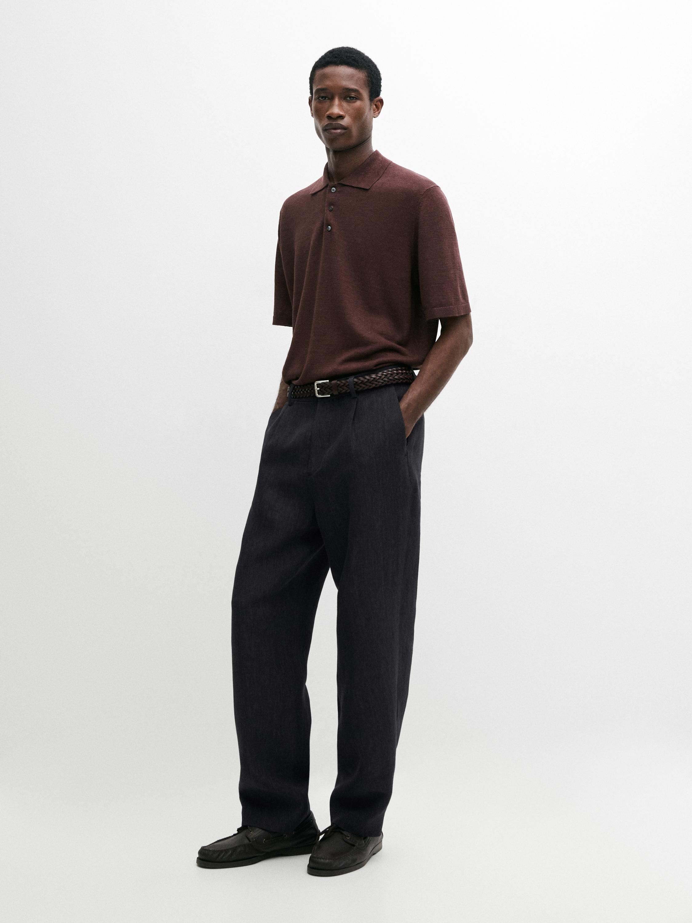 Conjunto de polo de punto burdeos con botones y pantalones oscuros de corte recto.