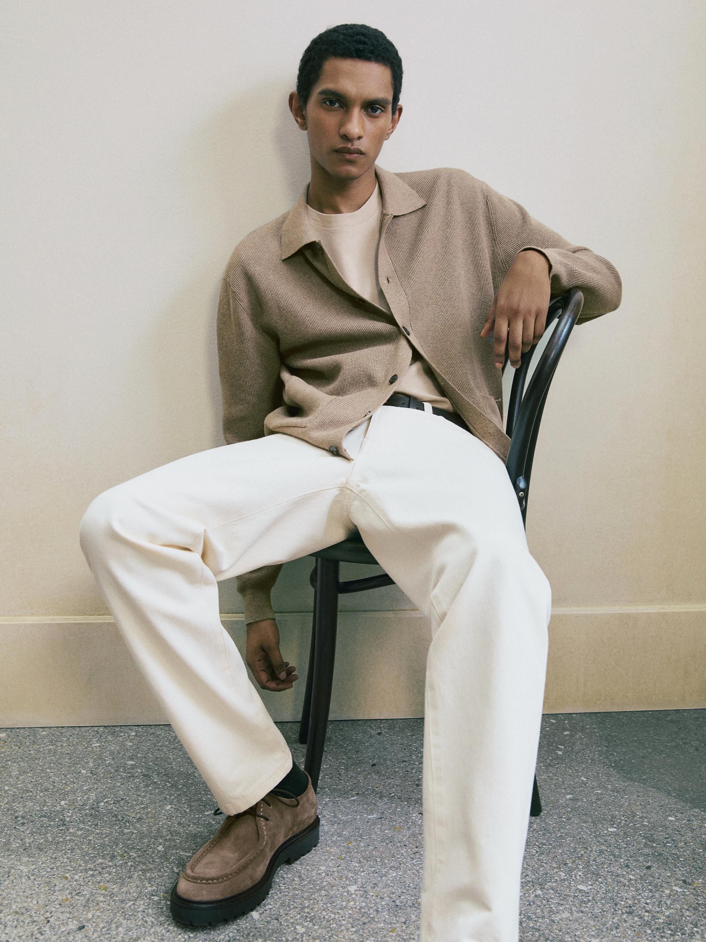 Sæt med beige skjorte med knapper, beige T-shirt, hvide bukser og brune sko.