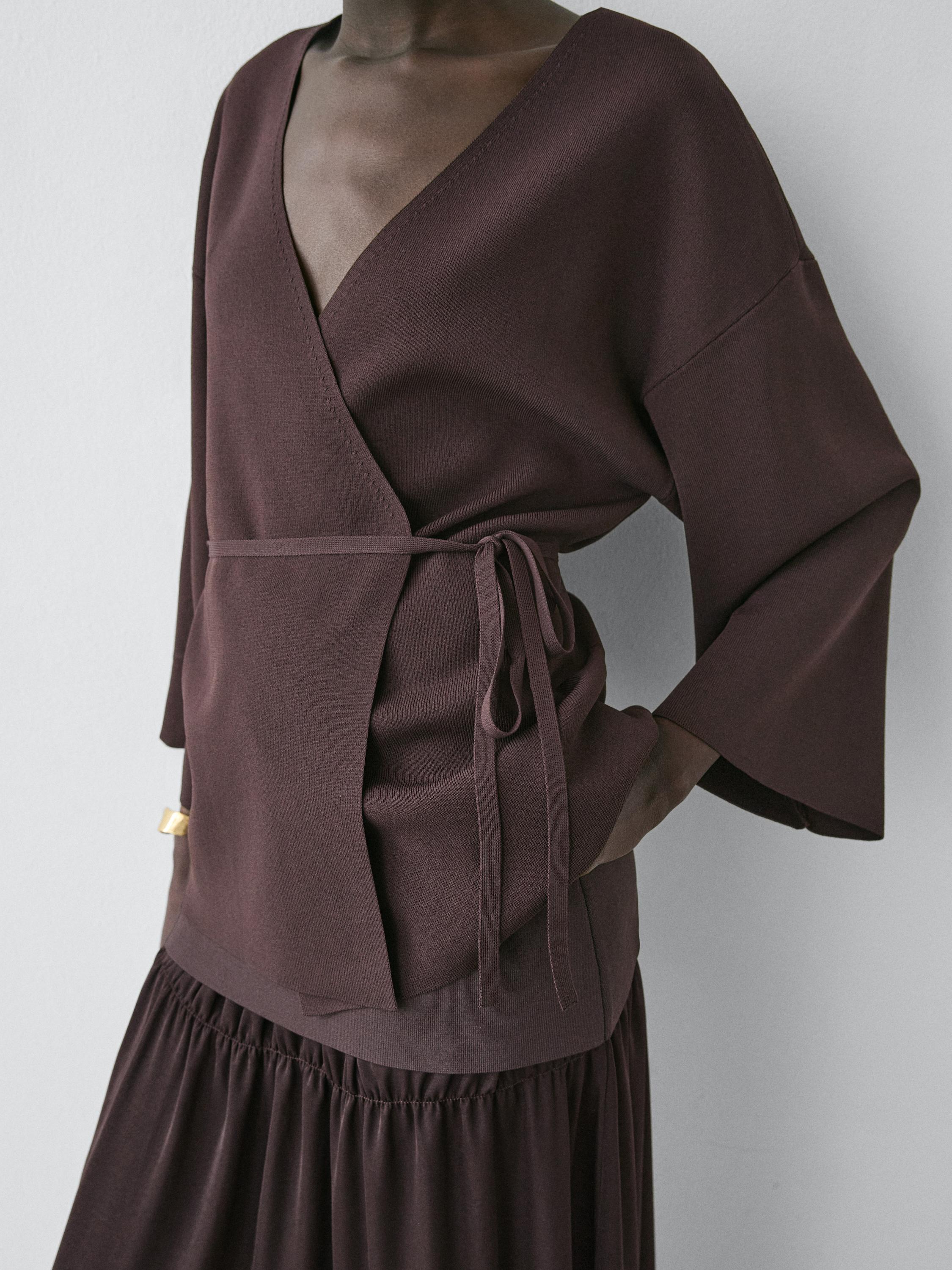 Półzbliżenie brązowego kimona z dekoltem w serek i regulowanym paskiem. Długie rękawy i luźny krój.