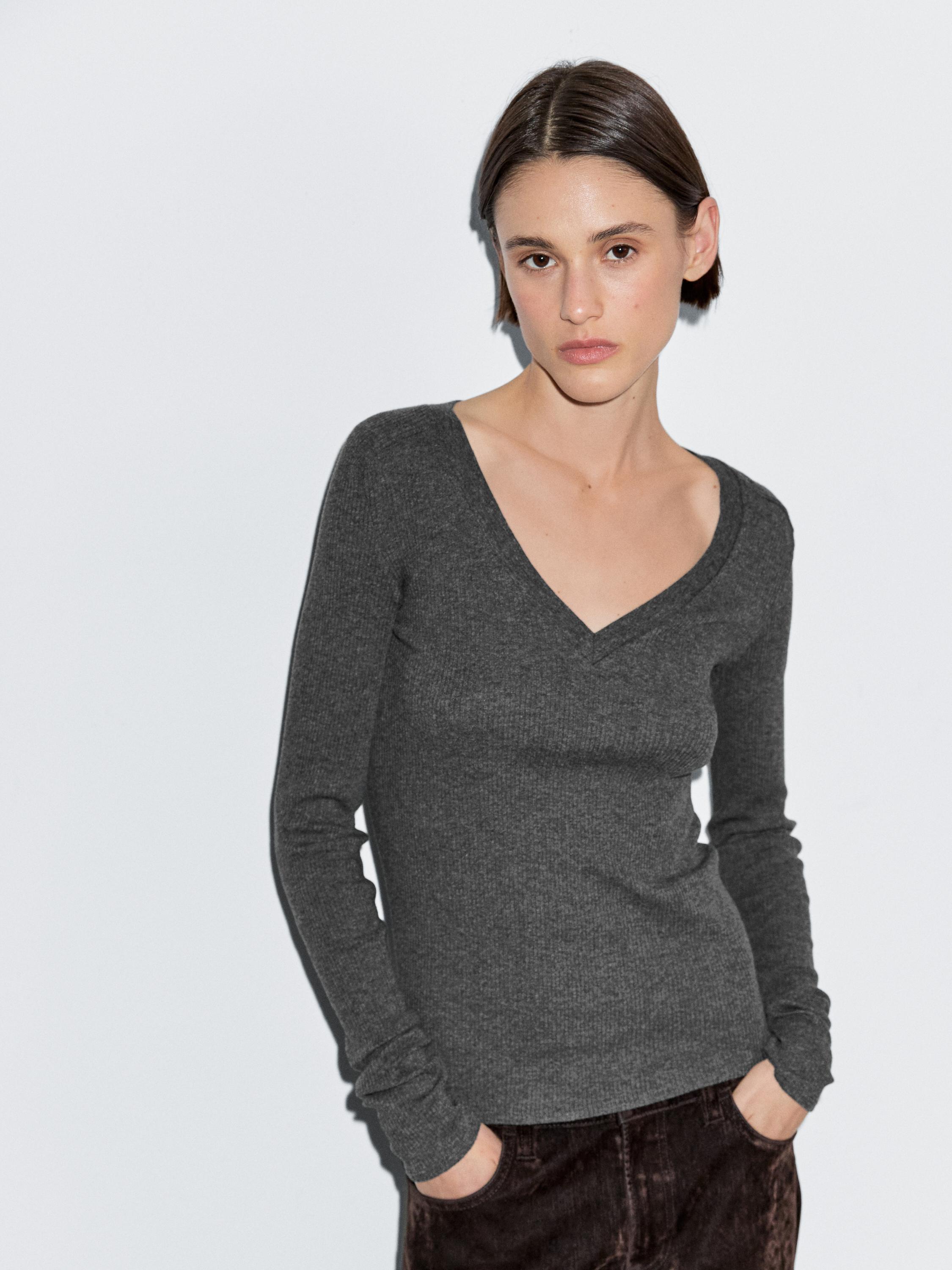 Conjunto de playera café de manga larga y cuello en V, con pantalones oscuros.