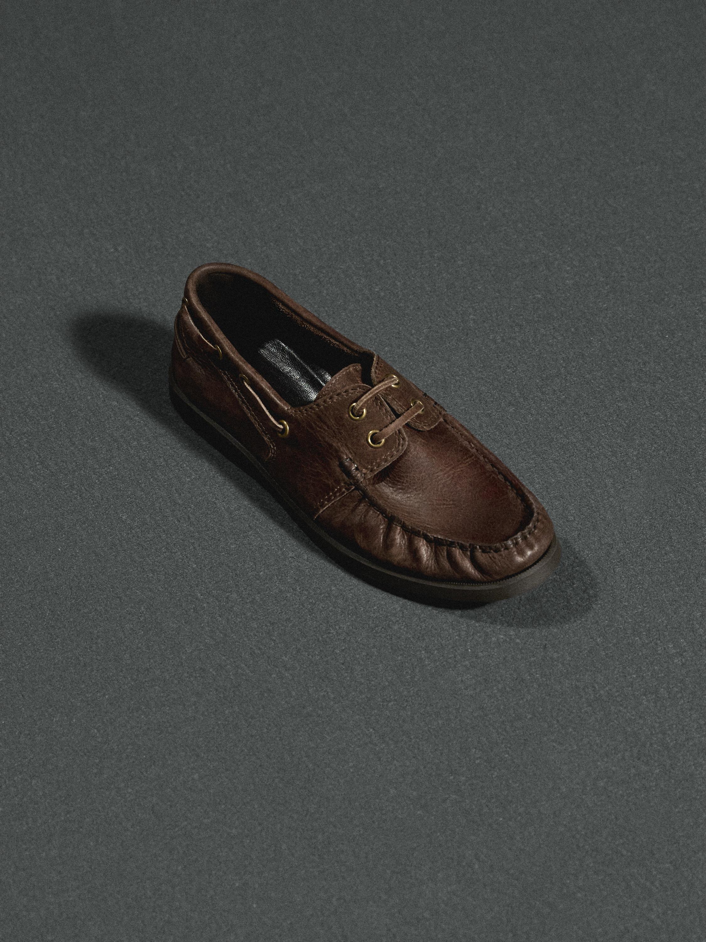 Vista frontal de zapato náutico marrón con cordones y costuras visibles.