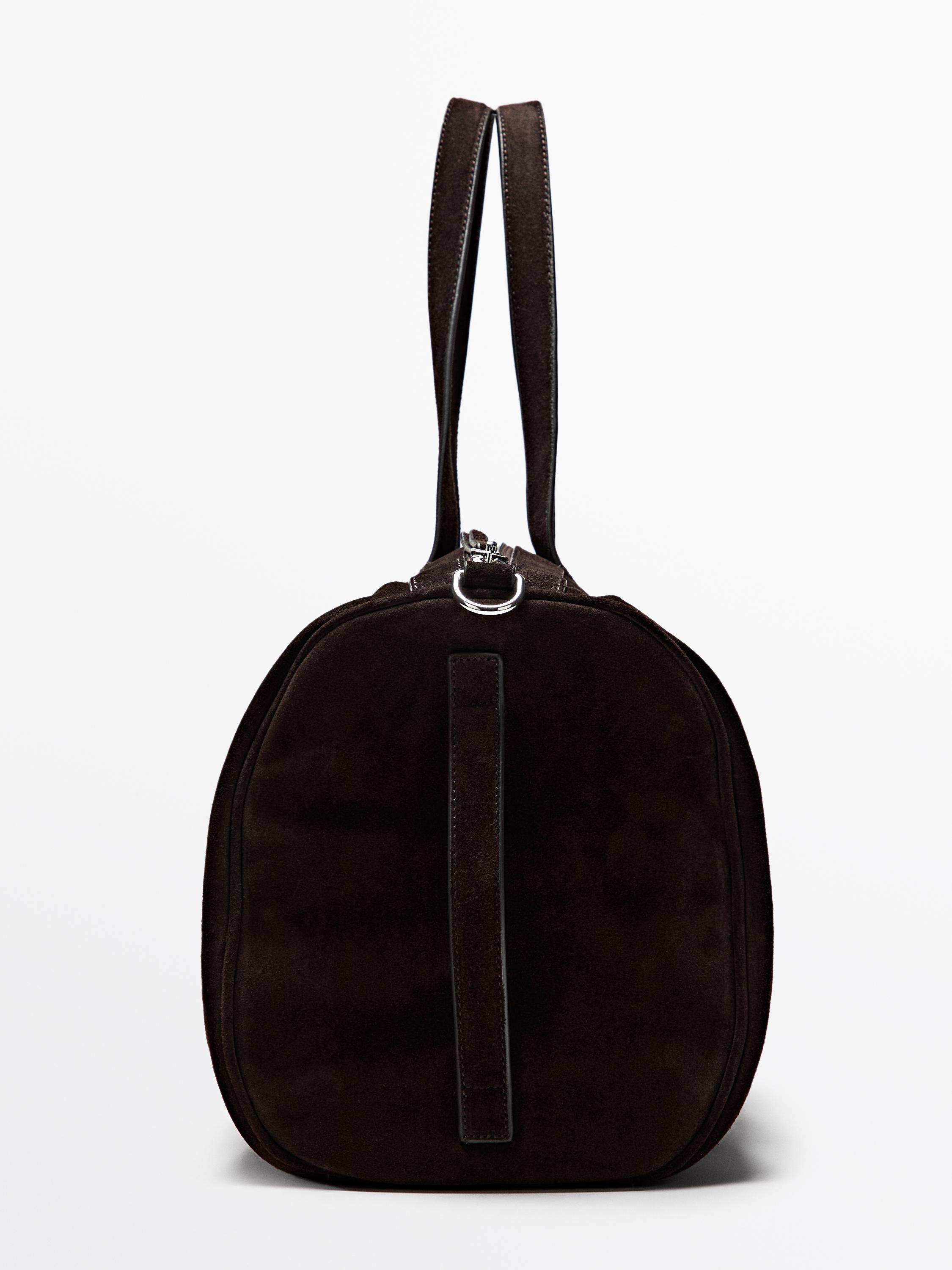 Bočni pogled na braon putnu torbu sa duplim ručkama i detaljima od metalnog prstena na vrhu.