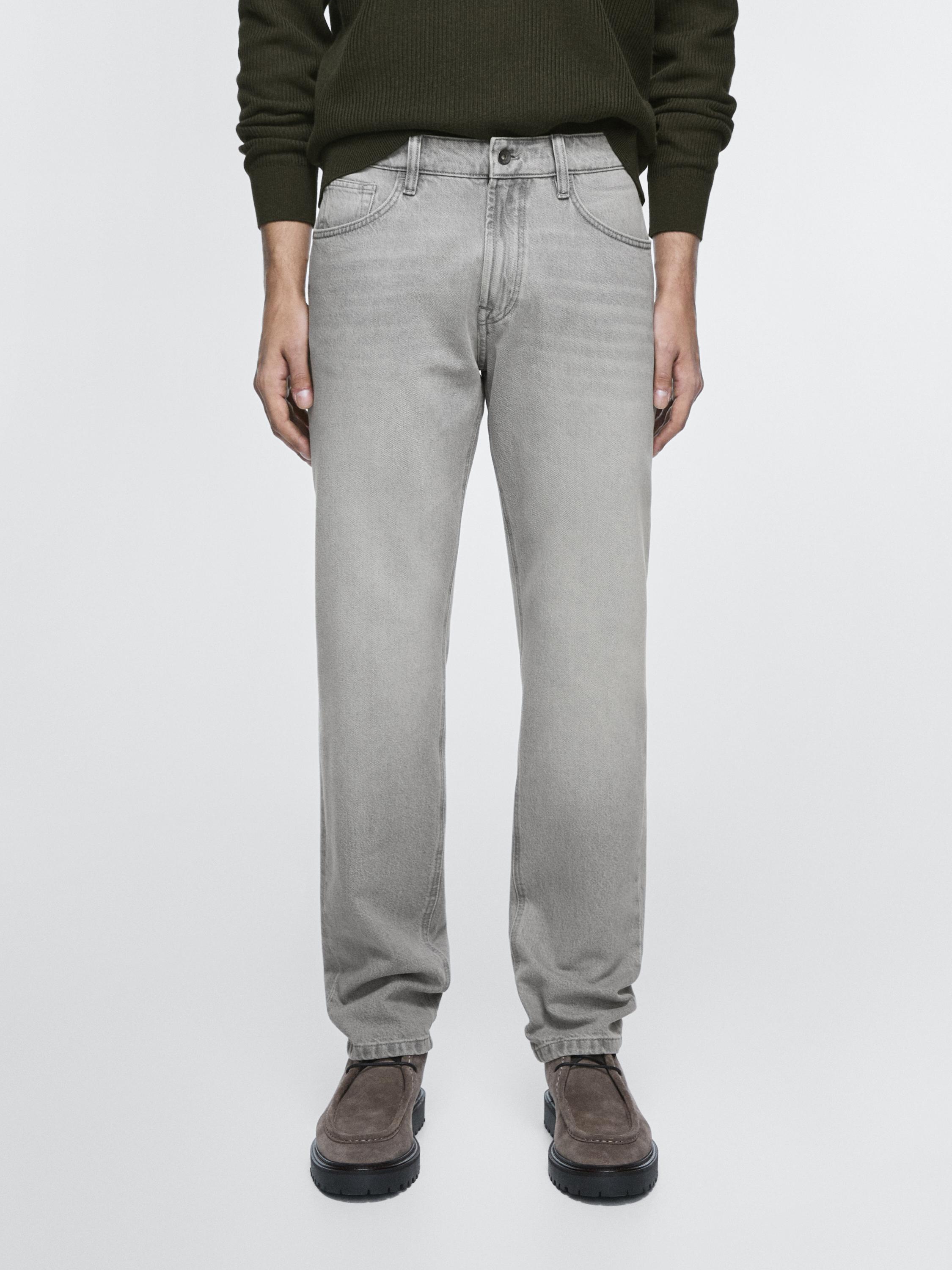 Conjunto de jeans gris tapered fit con bolsillos laterales y traseros, cierre de botón y cremallera.