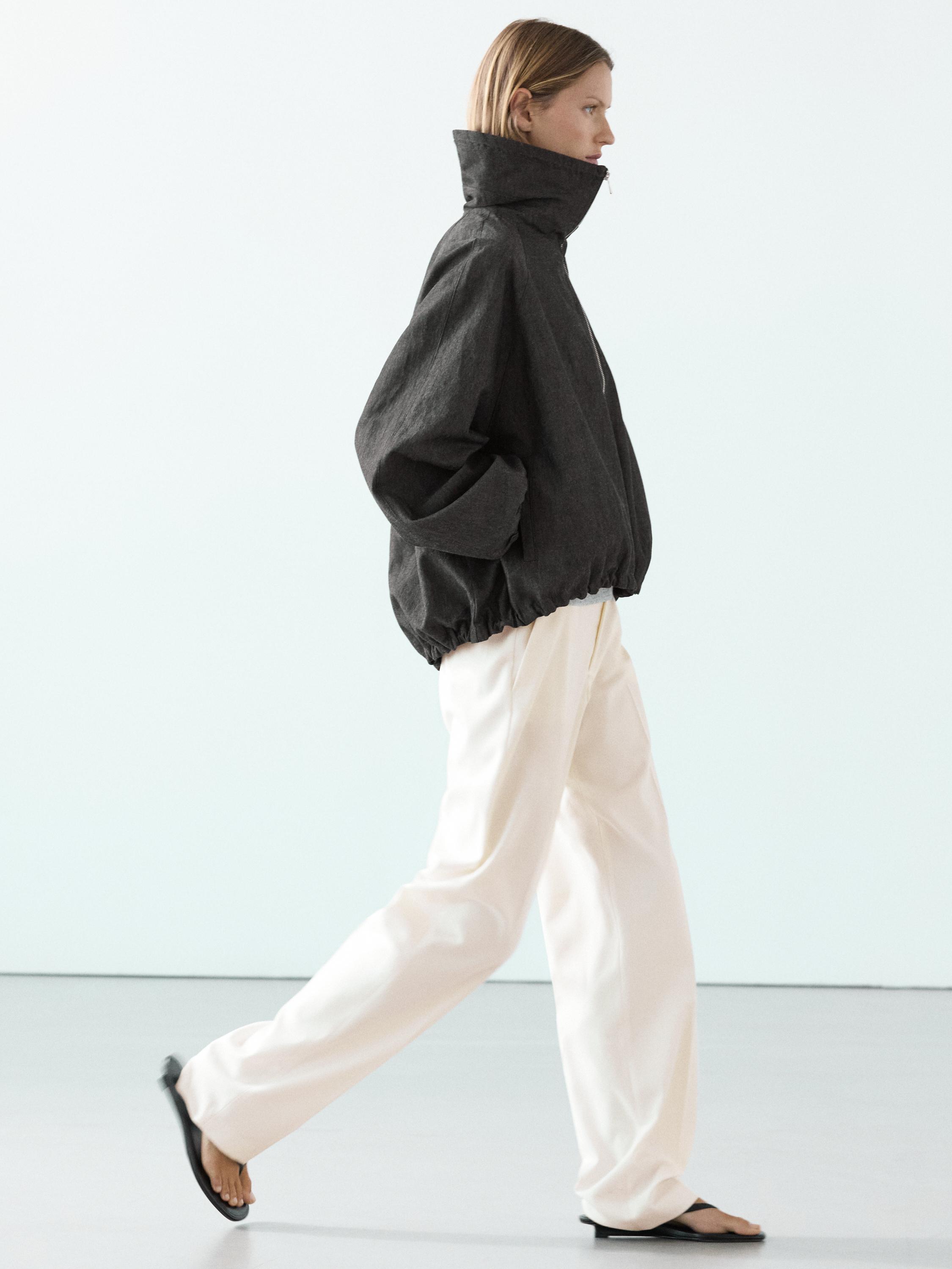 Grijsblauw bomberjack met col en wijde witte broek.