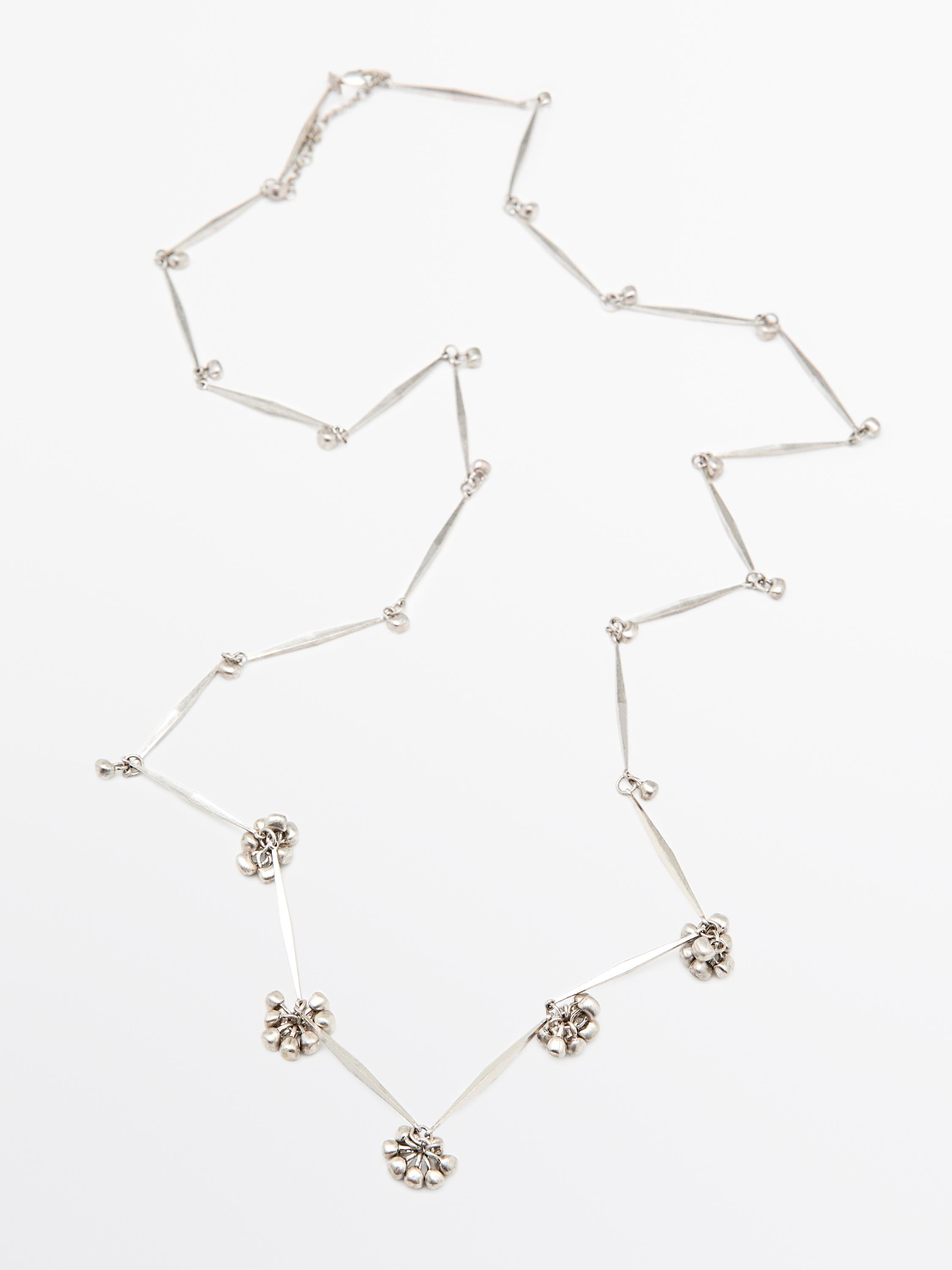 Silver metallic chain necklace with small flower details distributed along its length.