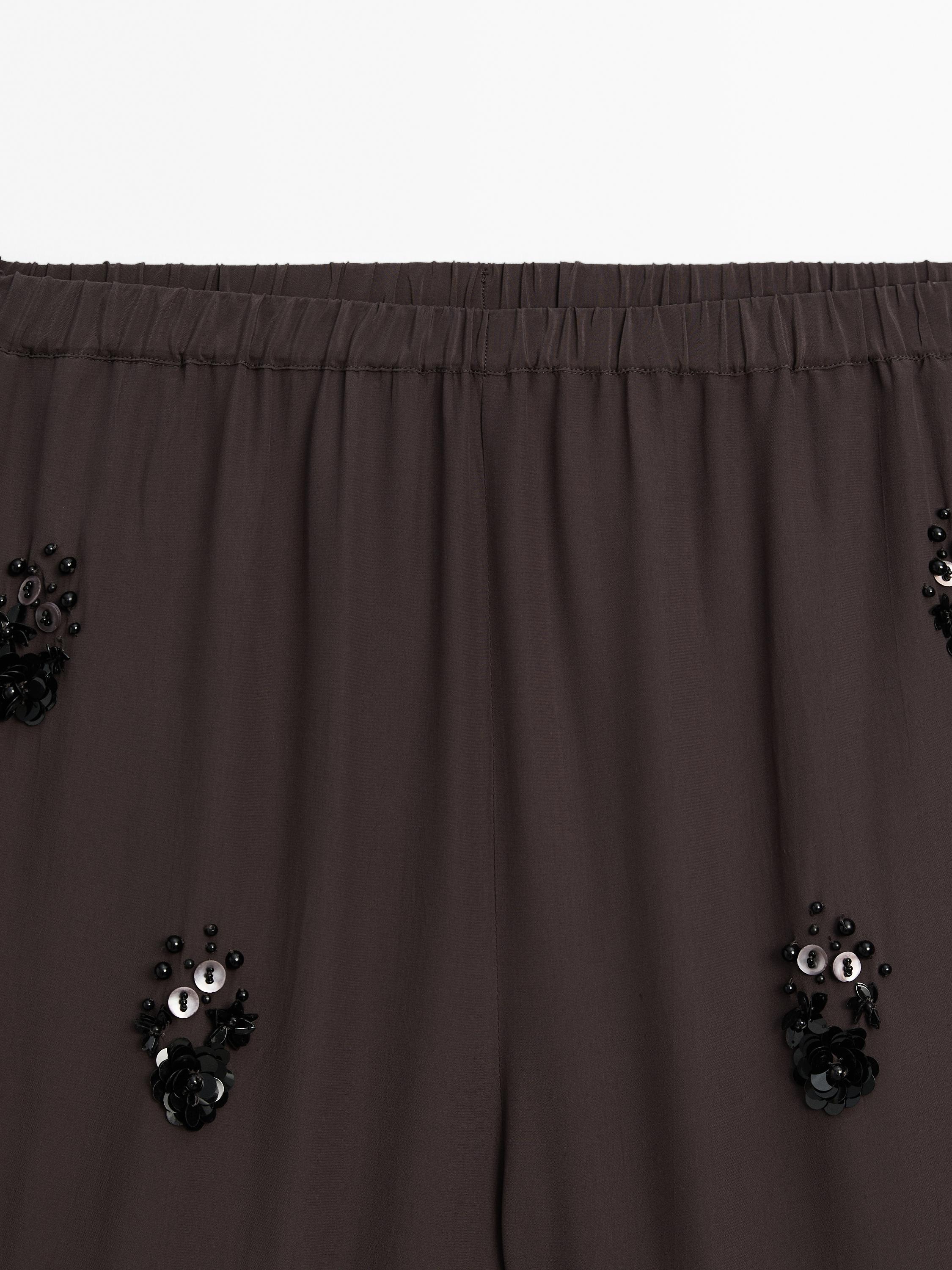 Flowing trousers with floral appliqués