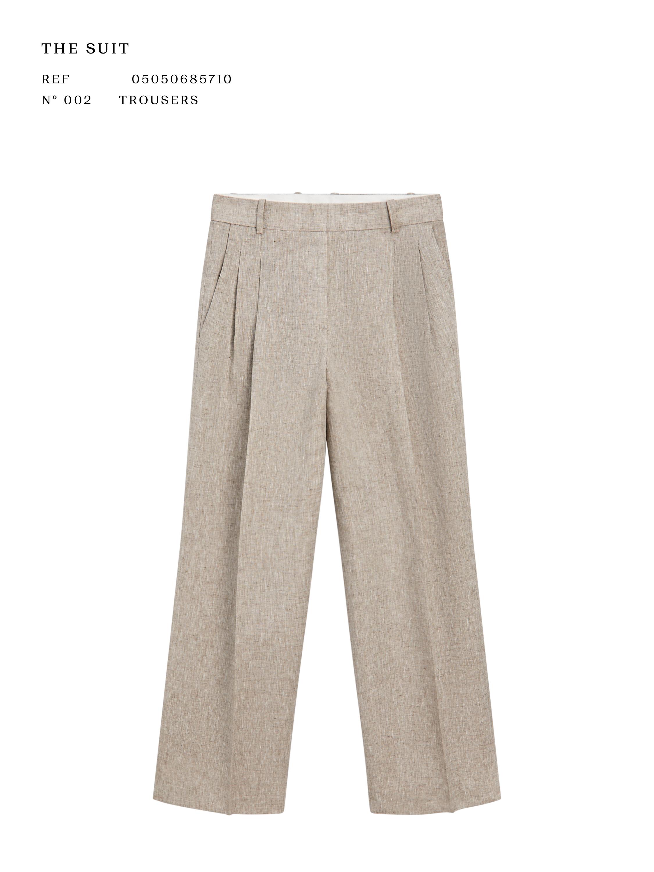 Вид спереди на бежевые брюки с защипами и боковыми карманами. Видимый текст: "THE SUIT REF 05050685710 N° 002 TROUSERS".