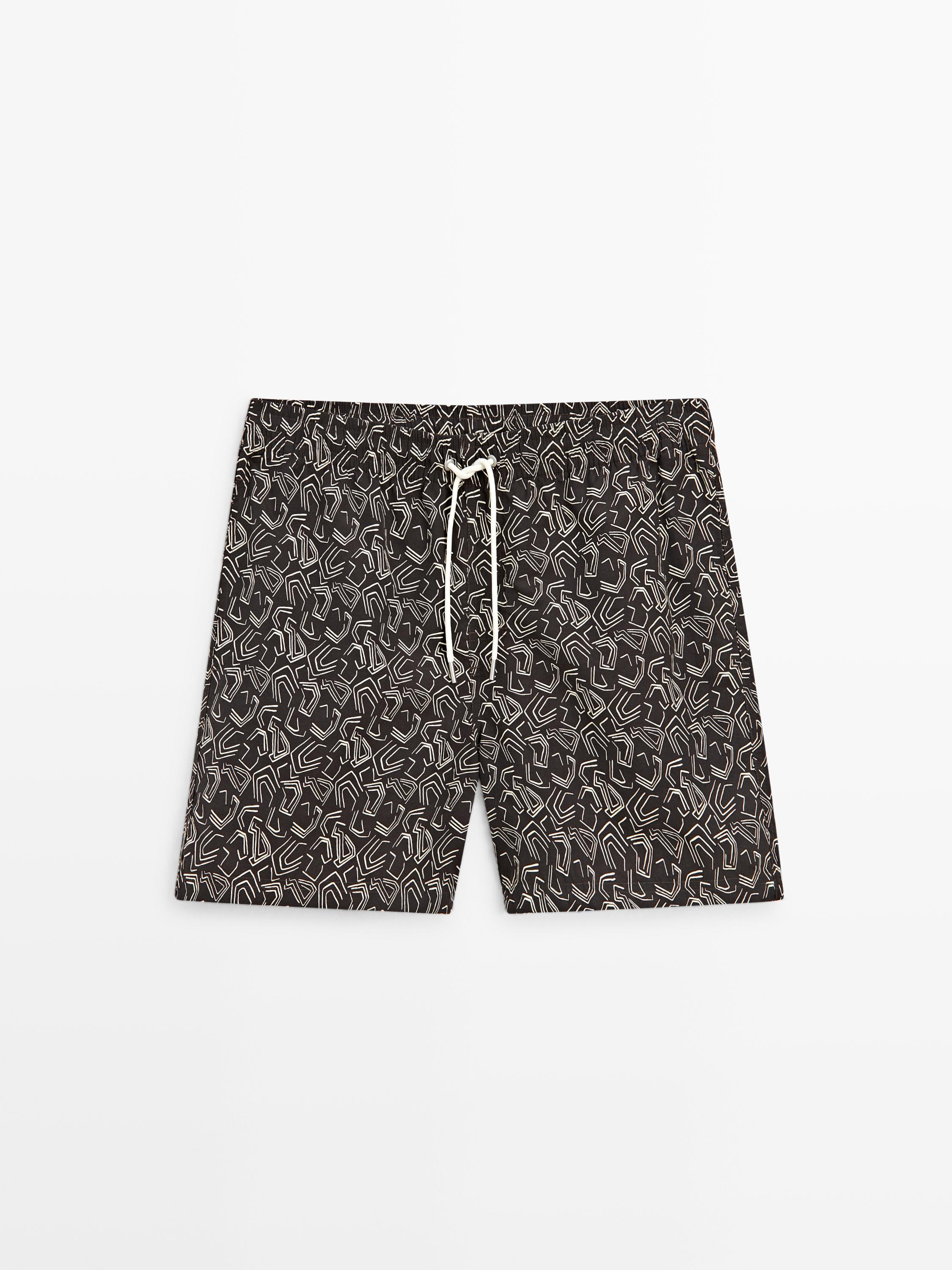 Vorderansicht einer braunen Badehose mit weißem Geometriedruck und verstellbarem Kordelzug an der Taille.