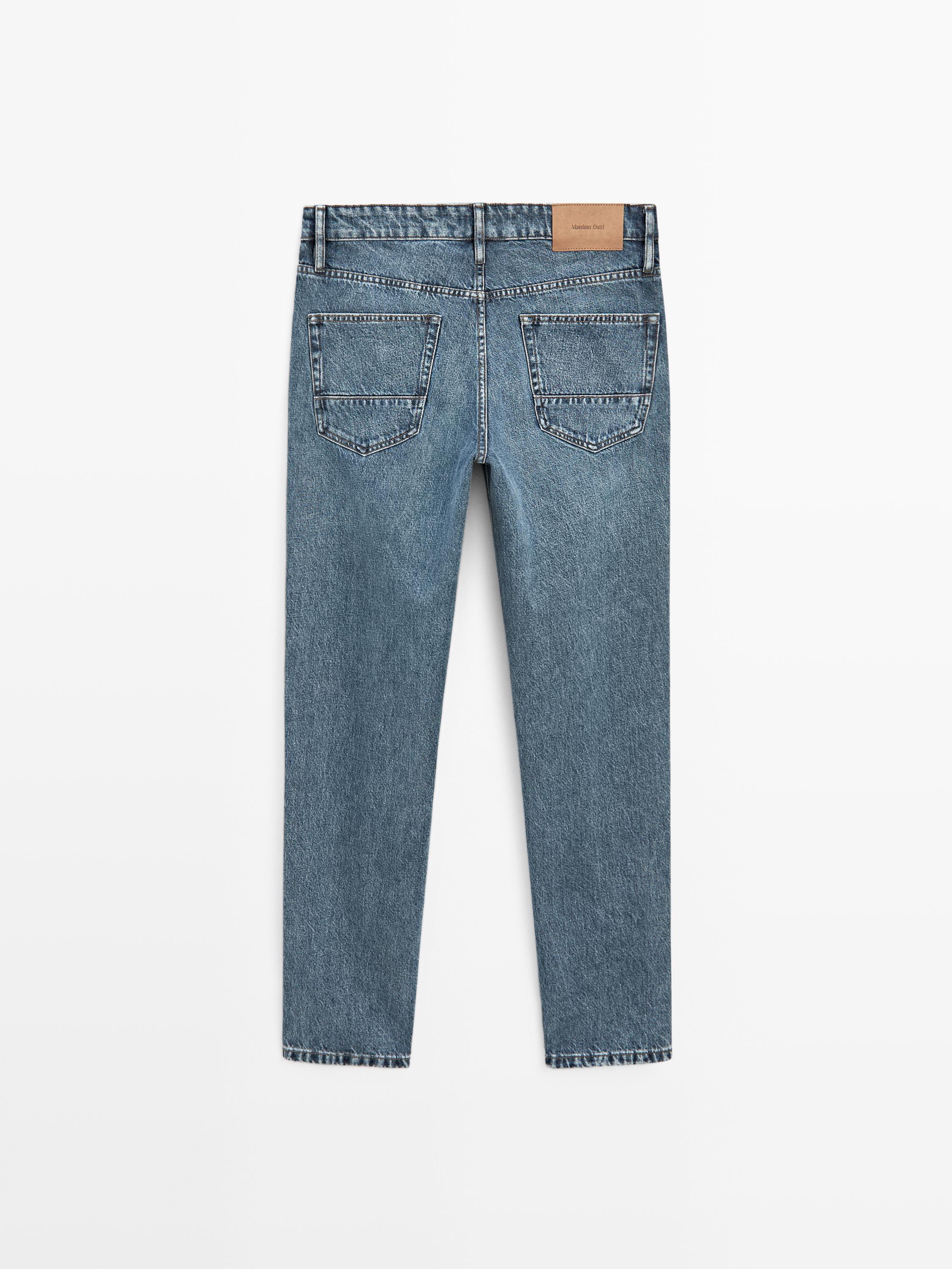 Vue arrière d'un jean bleu roi slim fit avec poches arrière et étiquette marron à la taille.