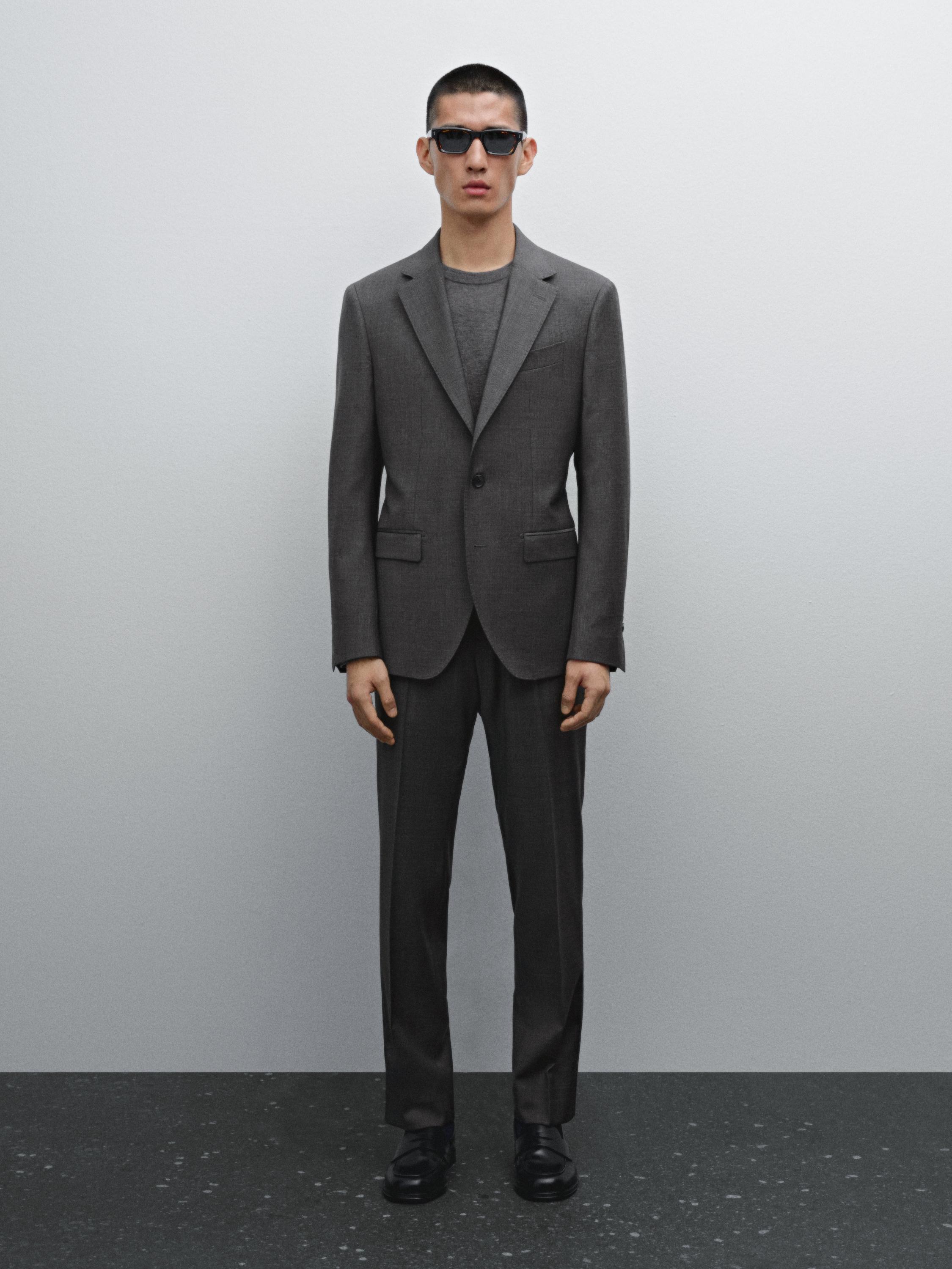 طقم بدلة رمادية مع سترة بياقة مدببة وبنطلون مستقيم.