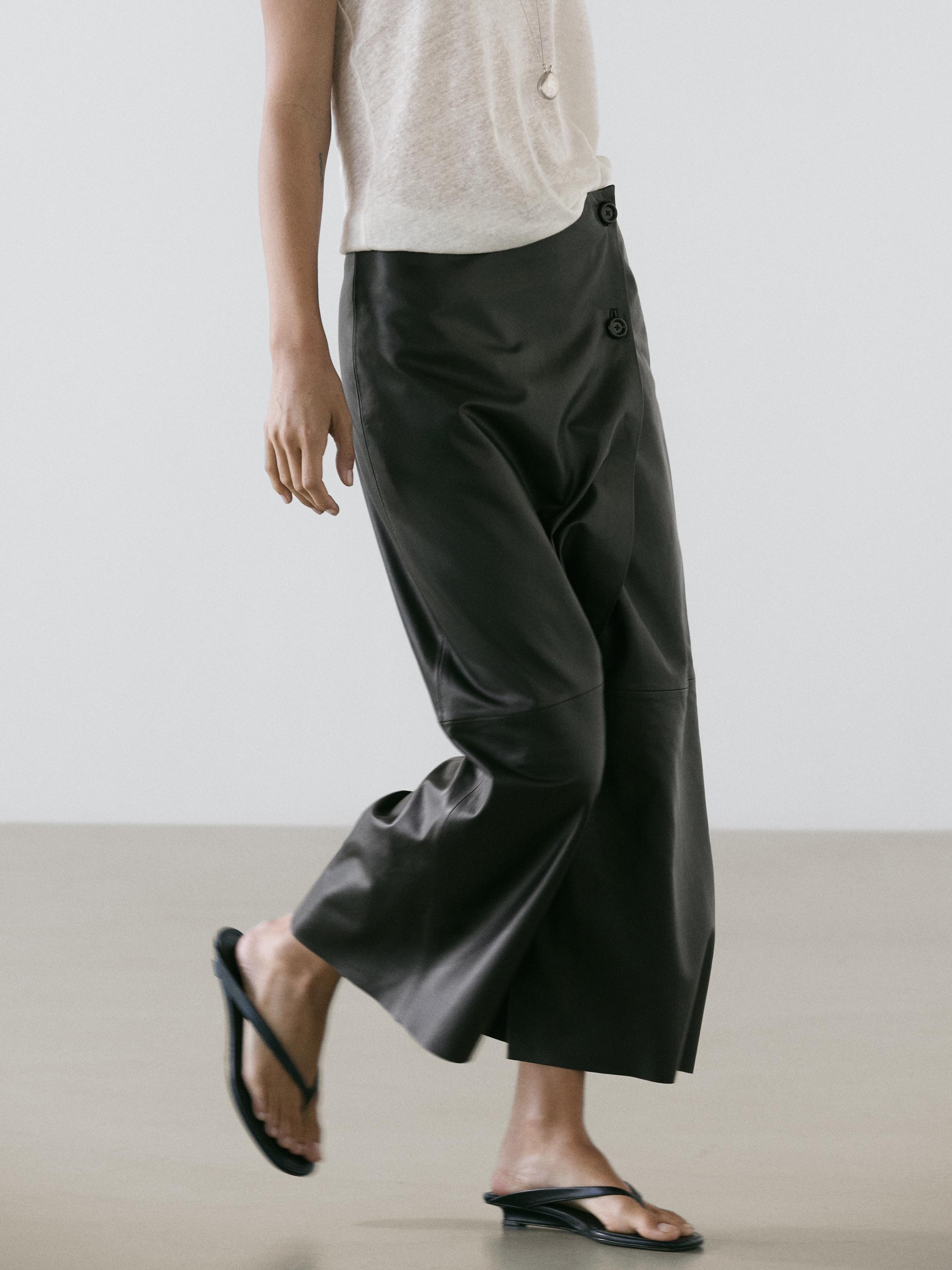 Halbnahaufnahme eines schwarzen Rocks mit sichtbaren seitlichen Knöpfen, Midi-Länge und weitem Schnitt.