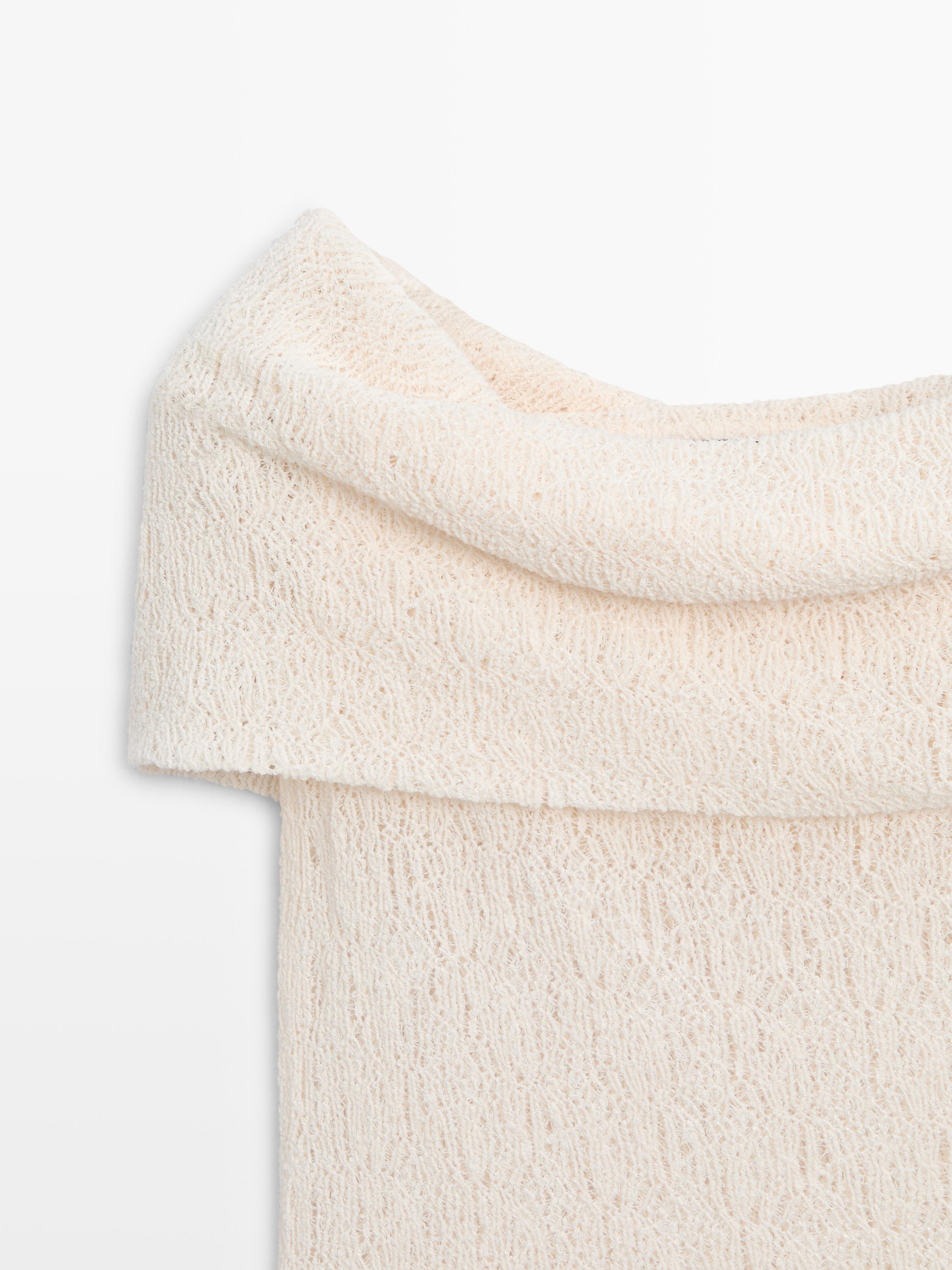 "Detail der Oberseite eines kurzärmeligen, naturfarbenen T-Shirts mit gewebter Textur."