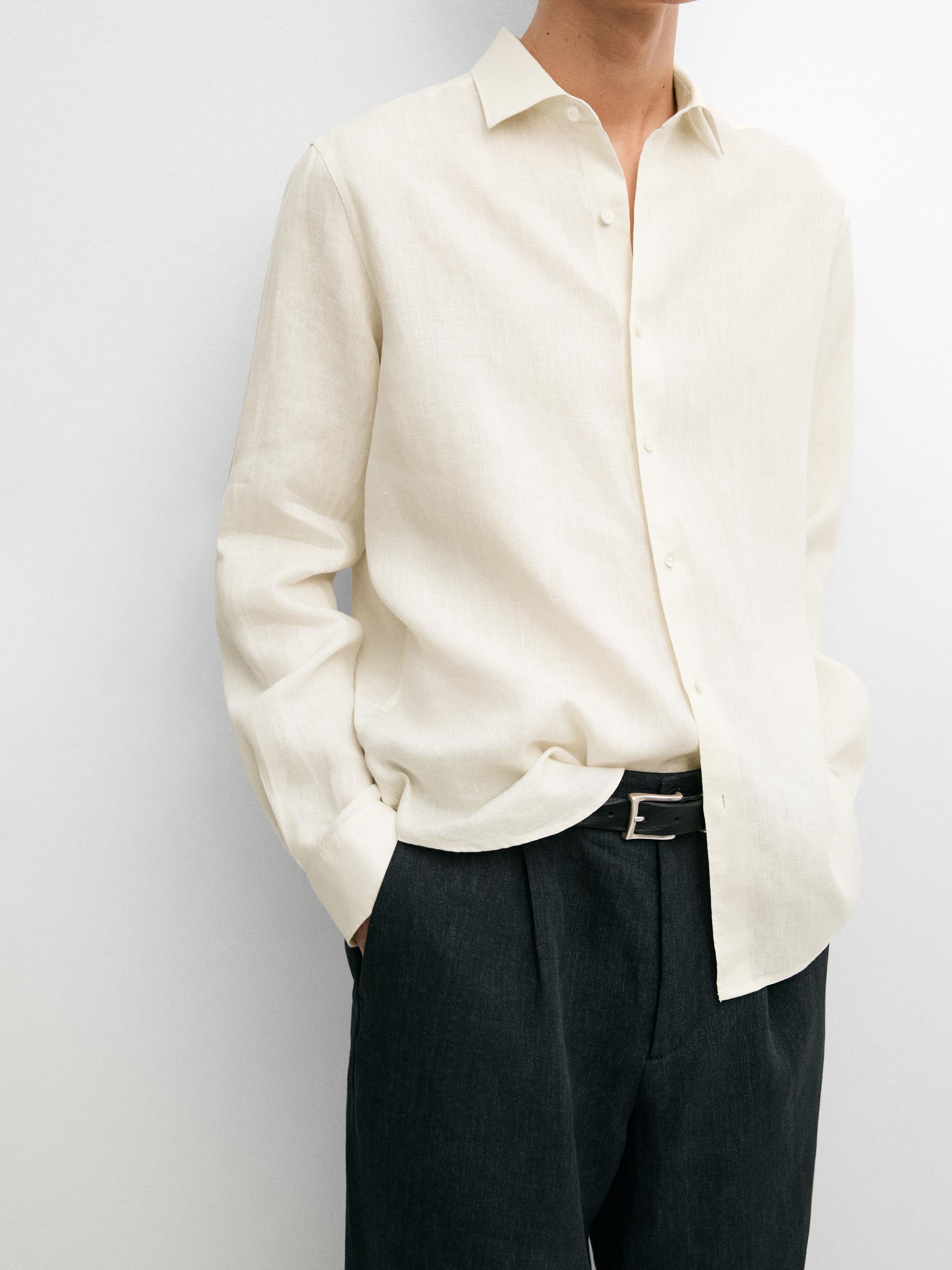 Plano mitjà de camisa beix de màniga llarga amb botonadura frontal i coll clàssic.