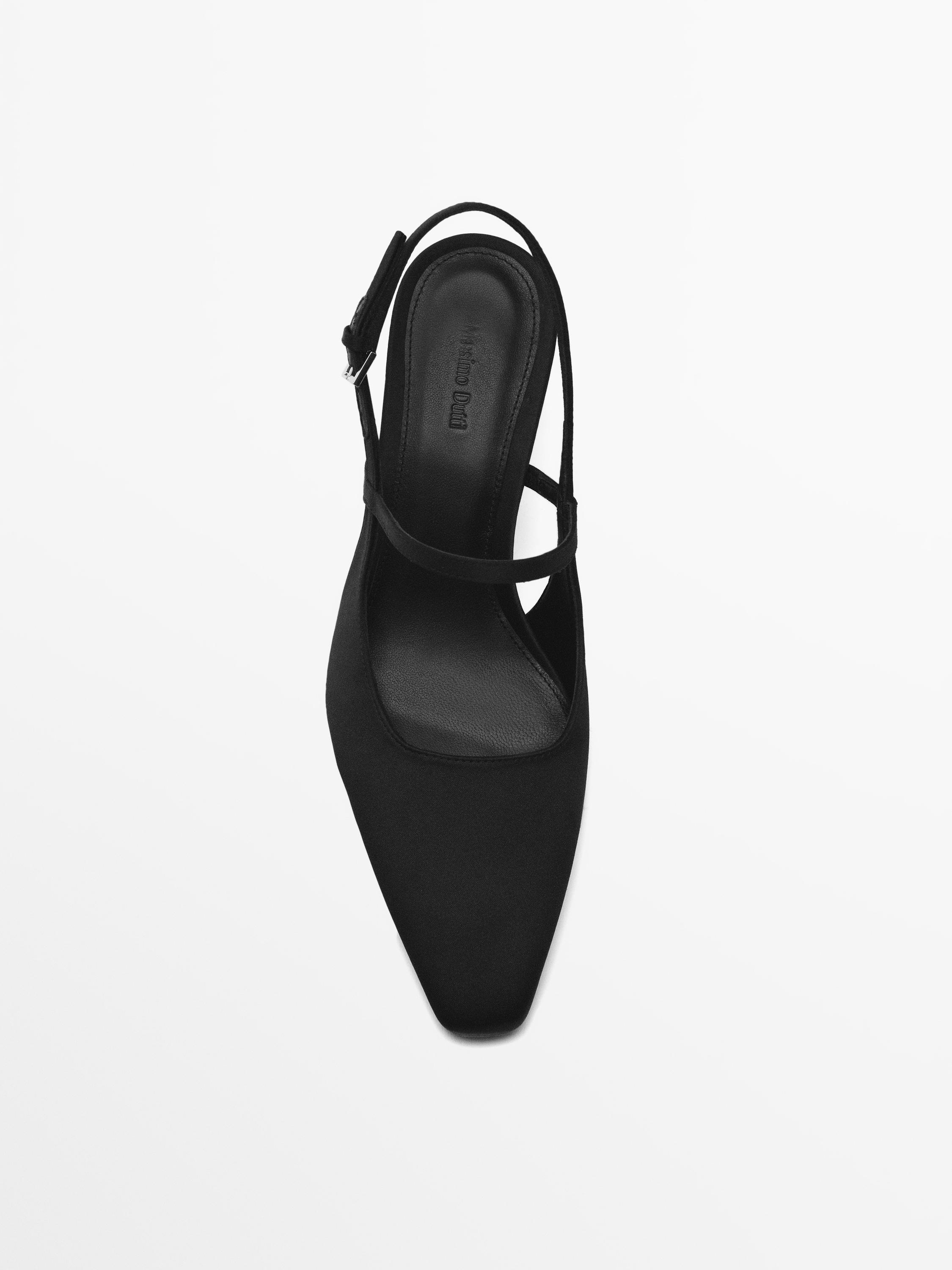 Vue de dessus d'une chaussure noire à bout carré avec une bride ajustable au talon.