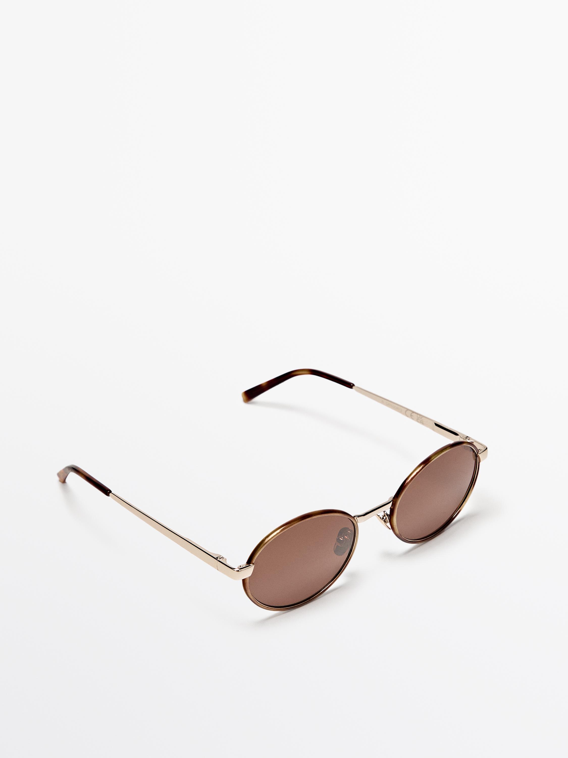 Lunettes de soleil marron avec monture métallique dorée et verres ovales. Largeur verre : 53 mm, pont : 20 mm, branche : 145 mm.