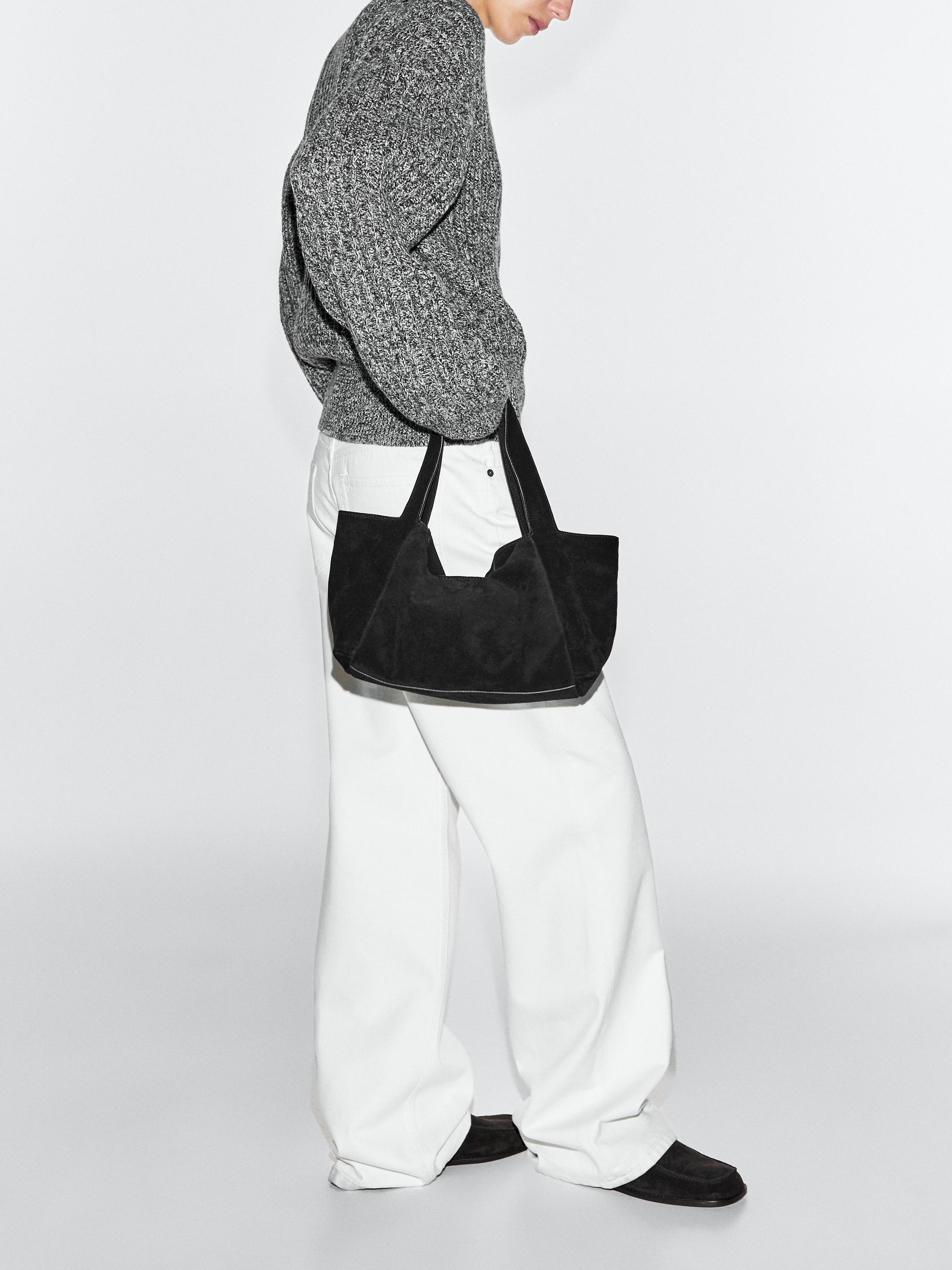 Black handbag set, chunky knit gray sweater, and wide white pants.