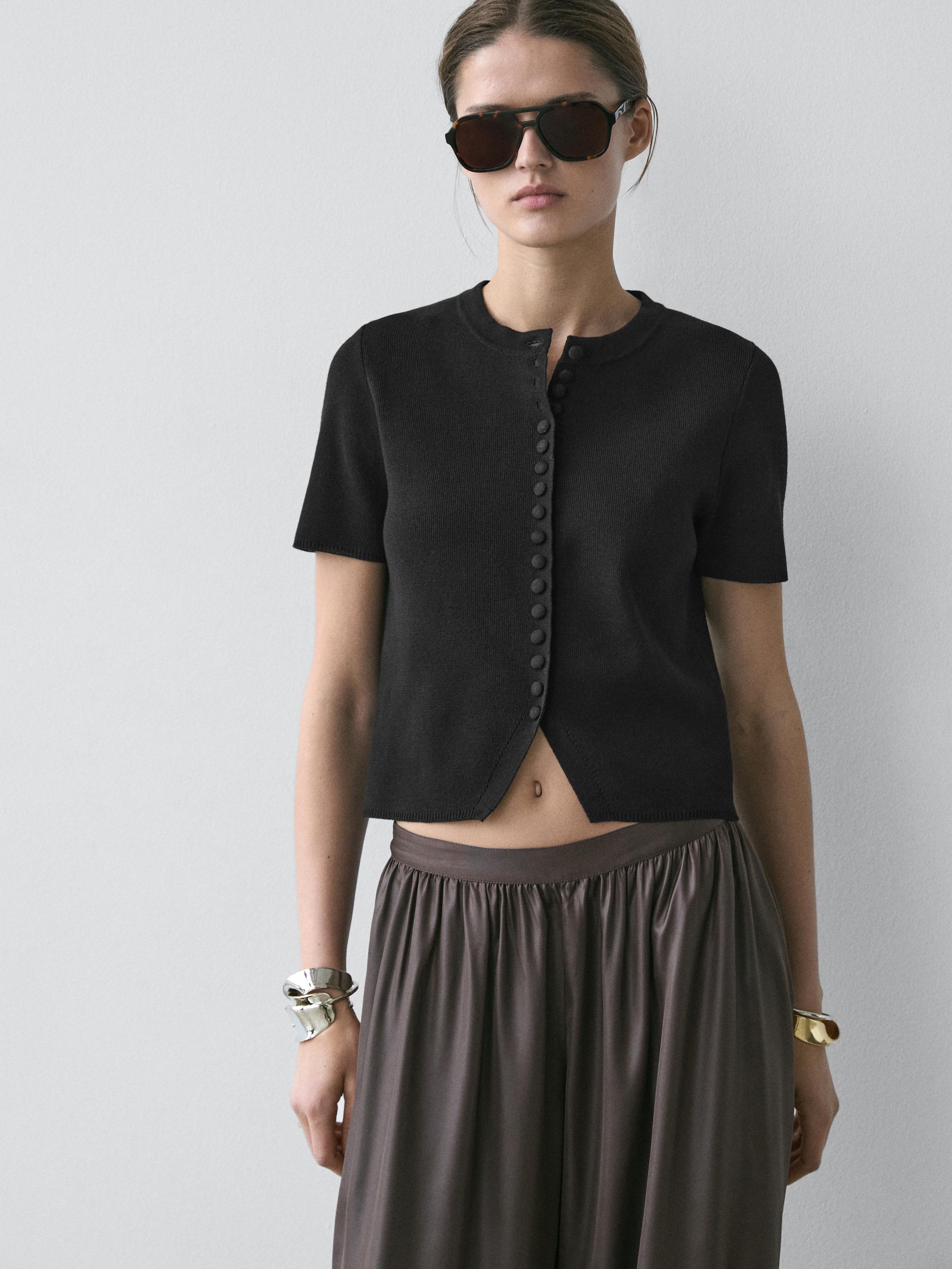 Kurzärmeliges, schwarzes Cardigan-Set mit Knopfleiste vorne und plissiertem, braunem Rock.