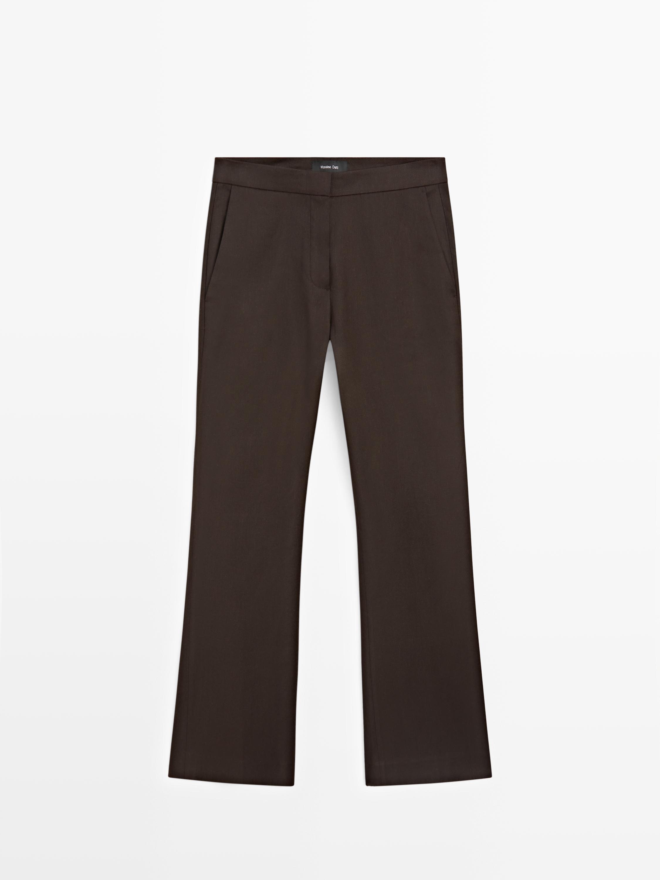 Vooraanzicht van een chocoladekleurige flared broek met zijzakken en een ritssluiting aan de voorkant.