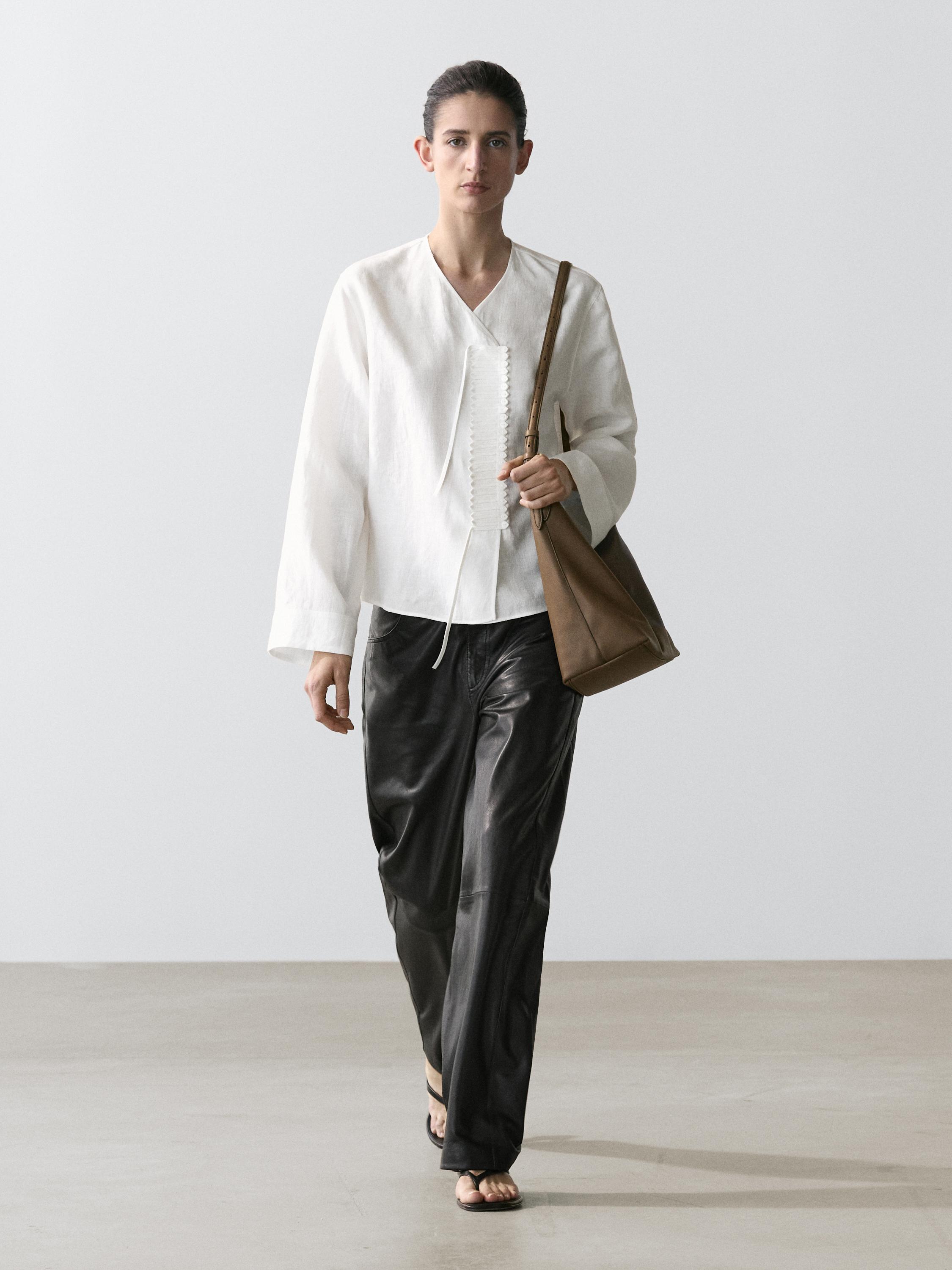 Conjunto de camisa blanca fluida con detalle en pechera y pantalones negros anchos.