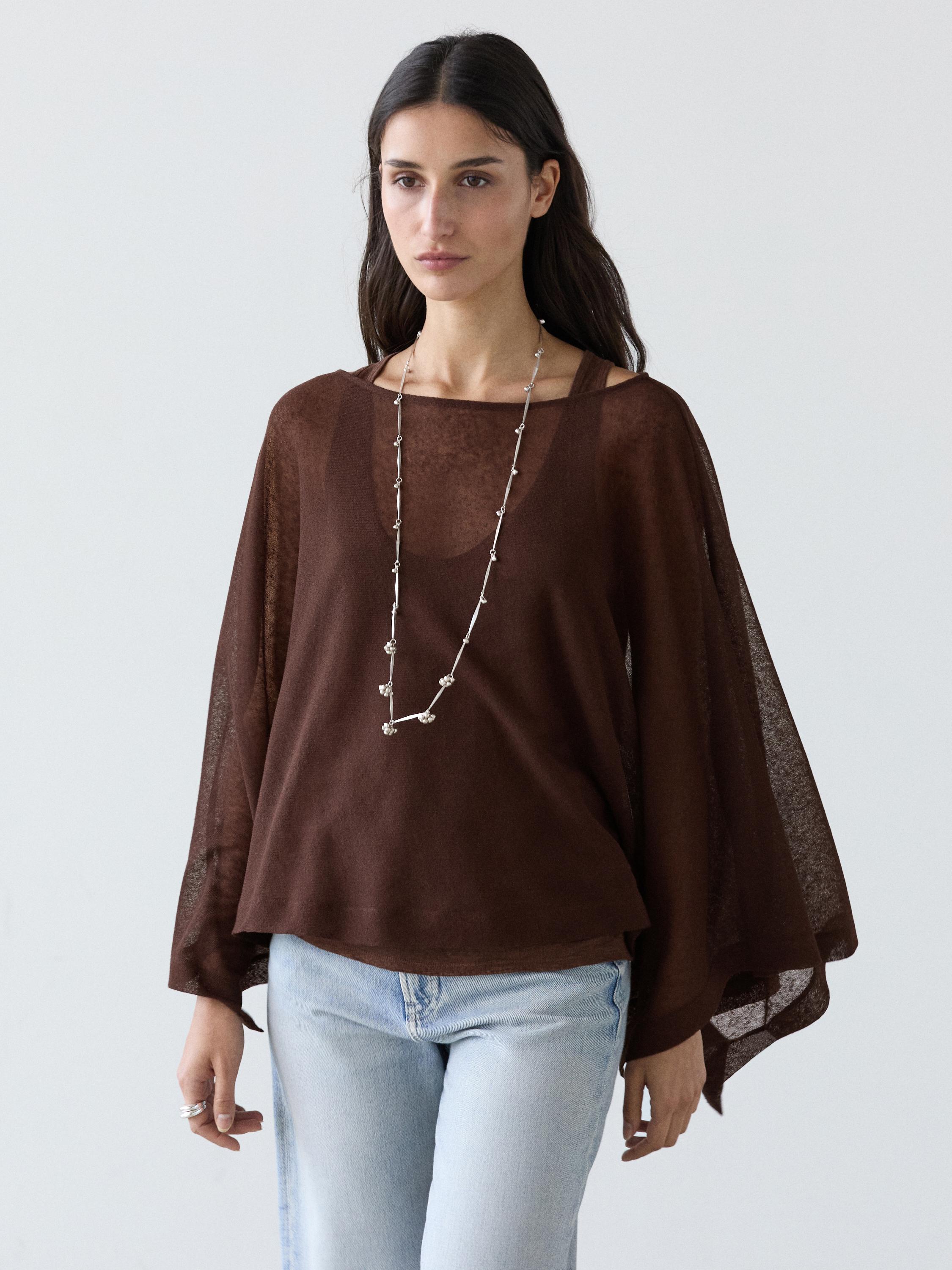 Conjunto de blusa castanha de manga comprida e corte fluido, com jeans claros.