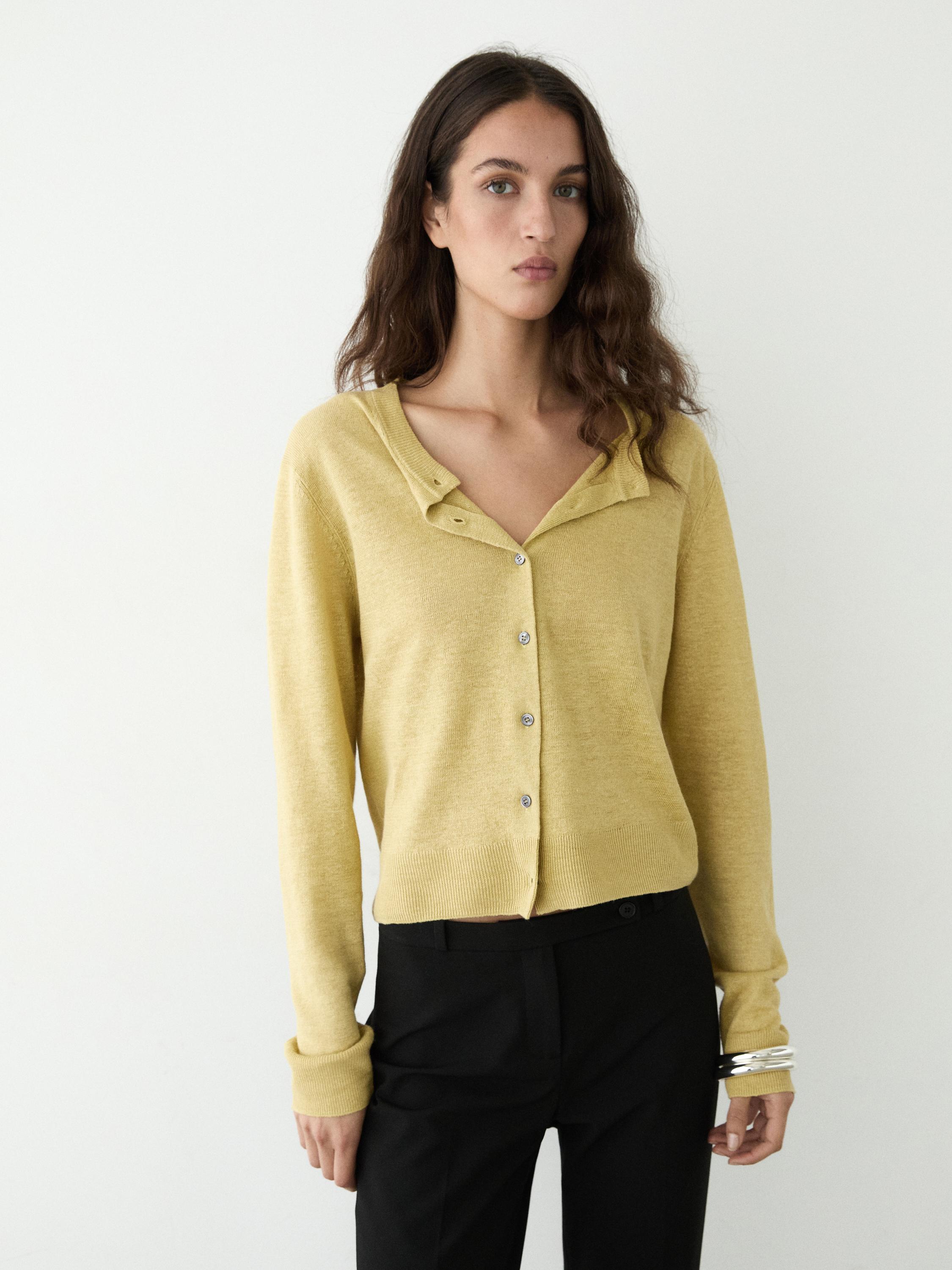 Düğmeli limon kısa hırka ve siyah pantolon takımı.