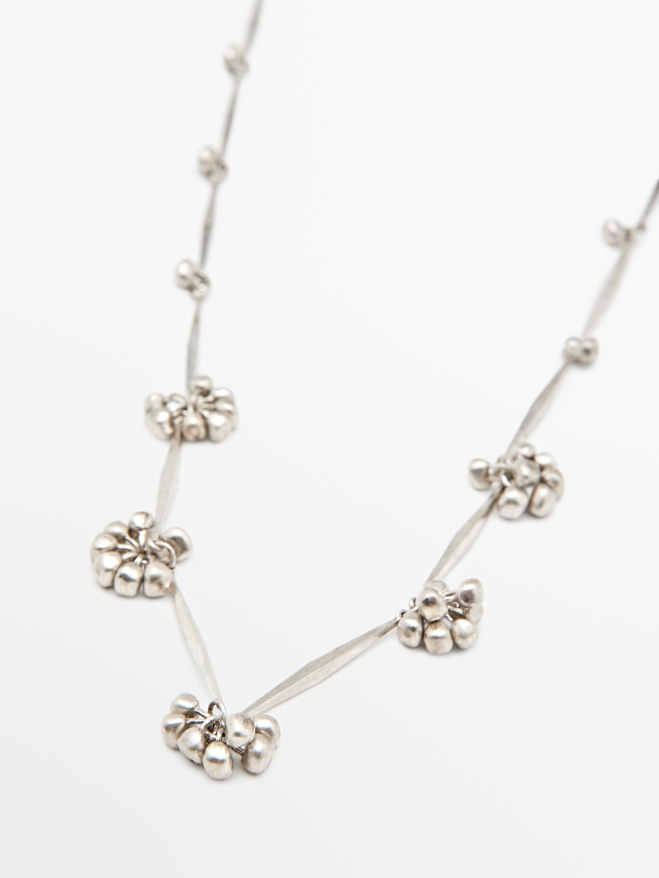 Silver-plated metal chain necklace with bead cluster details at regular intervals.