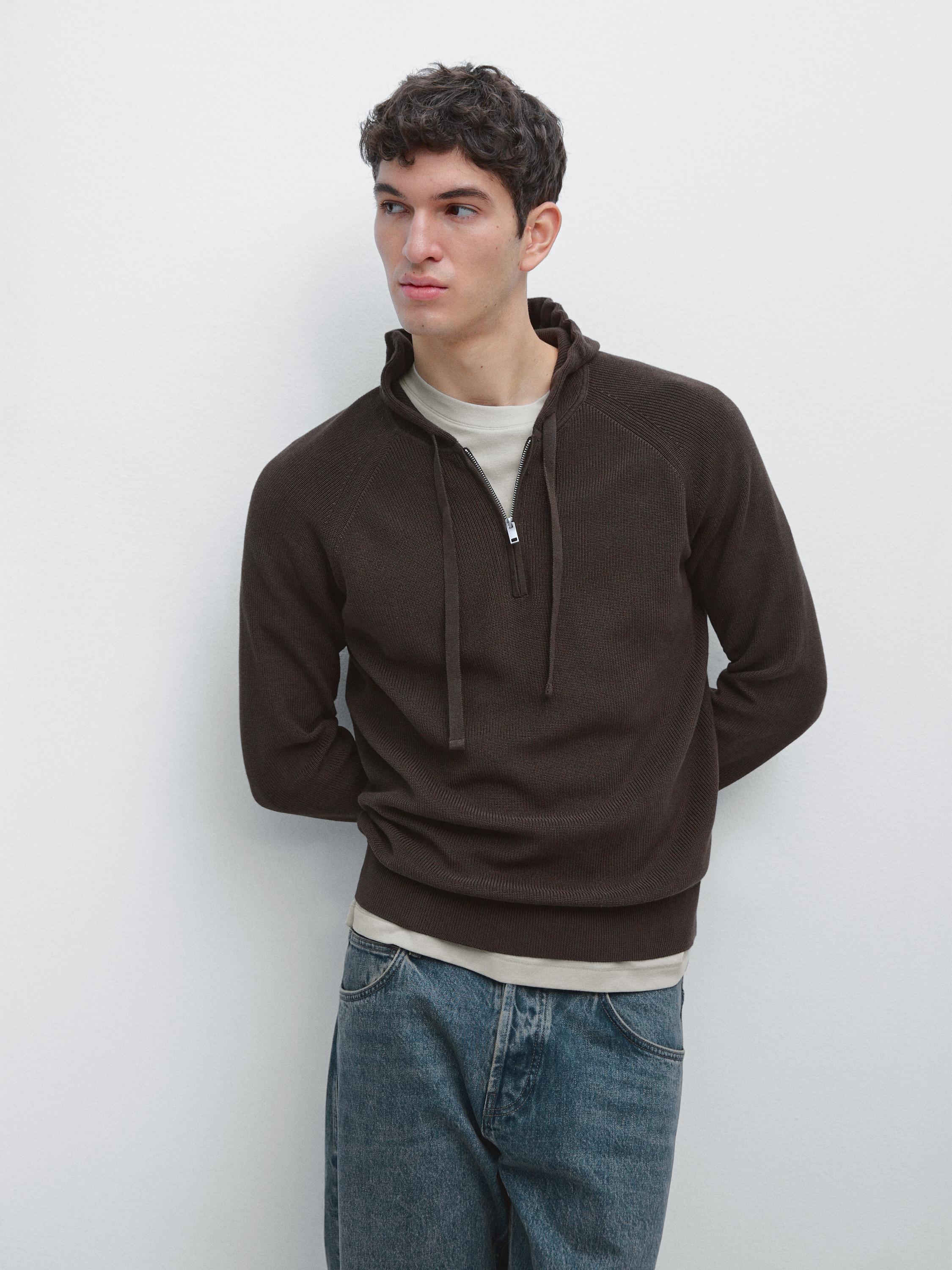 Ensemble de sweat à capuche marron avec fermeture éclair partielle, sur un t-shirt beige, combiné avec un jean bleu.