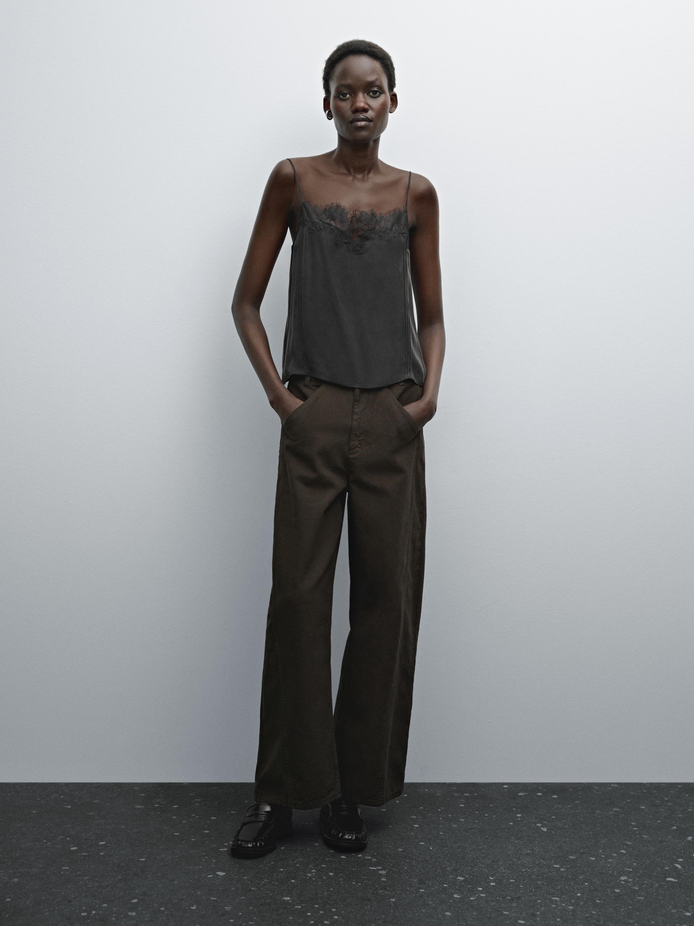 طقم مكون من توب أسود بحمالات رفيعة مع دانتيل وبنطلون بني واسع.